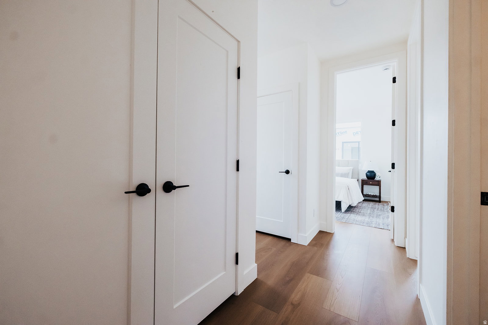 Hallway featuring wood-finish flooring, white walls, and bright overhead lighting