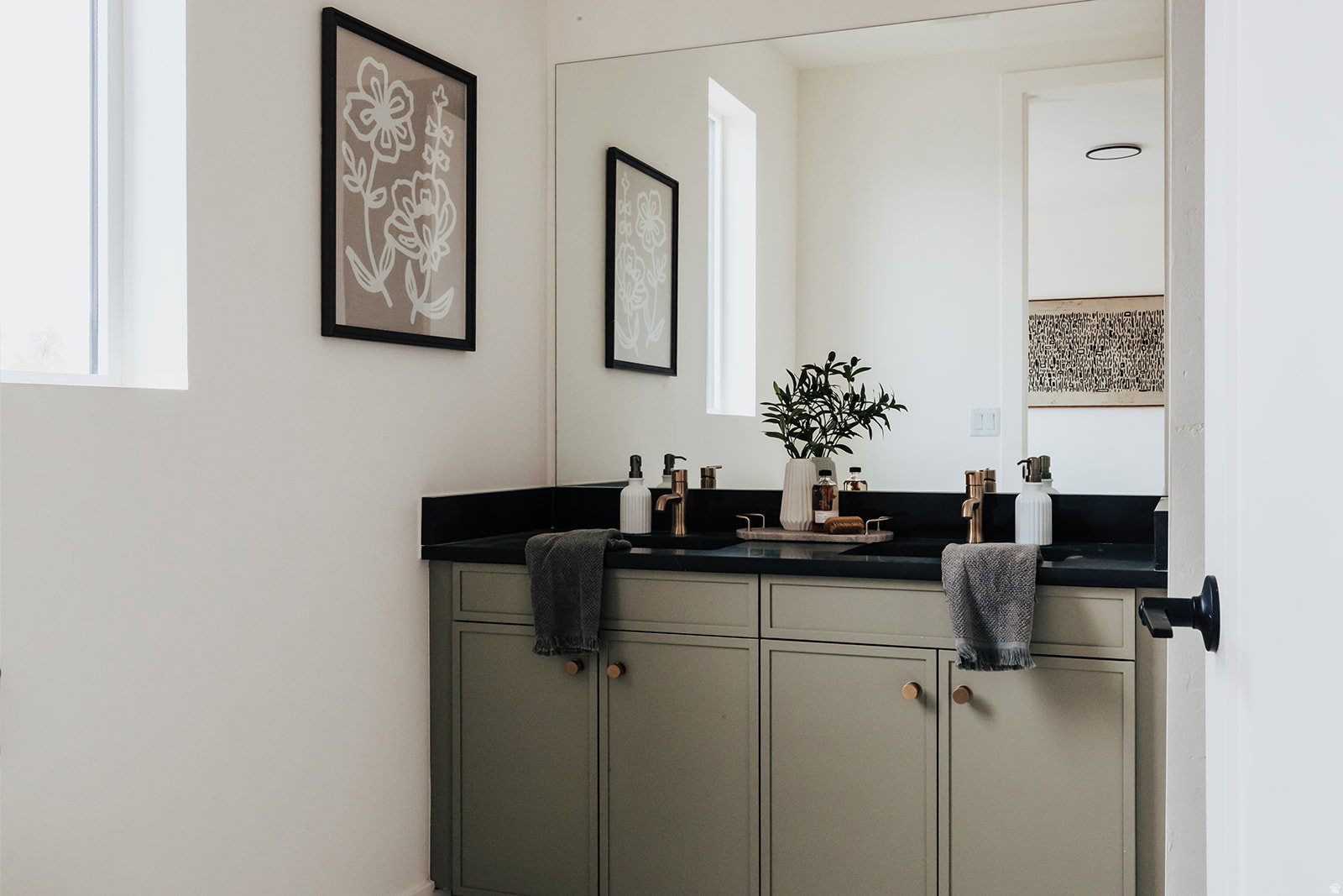 Double vanity featuring a black countertop, dual undermount sinks, and gold-finish faucets