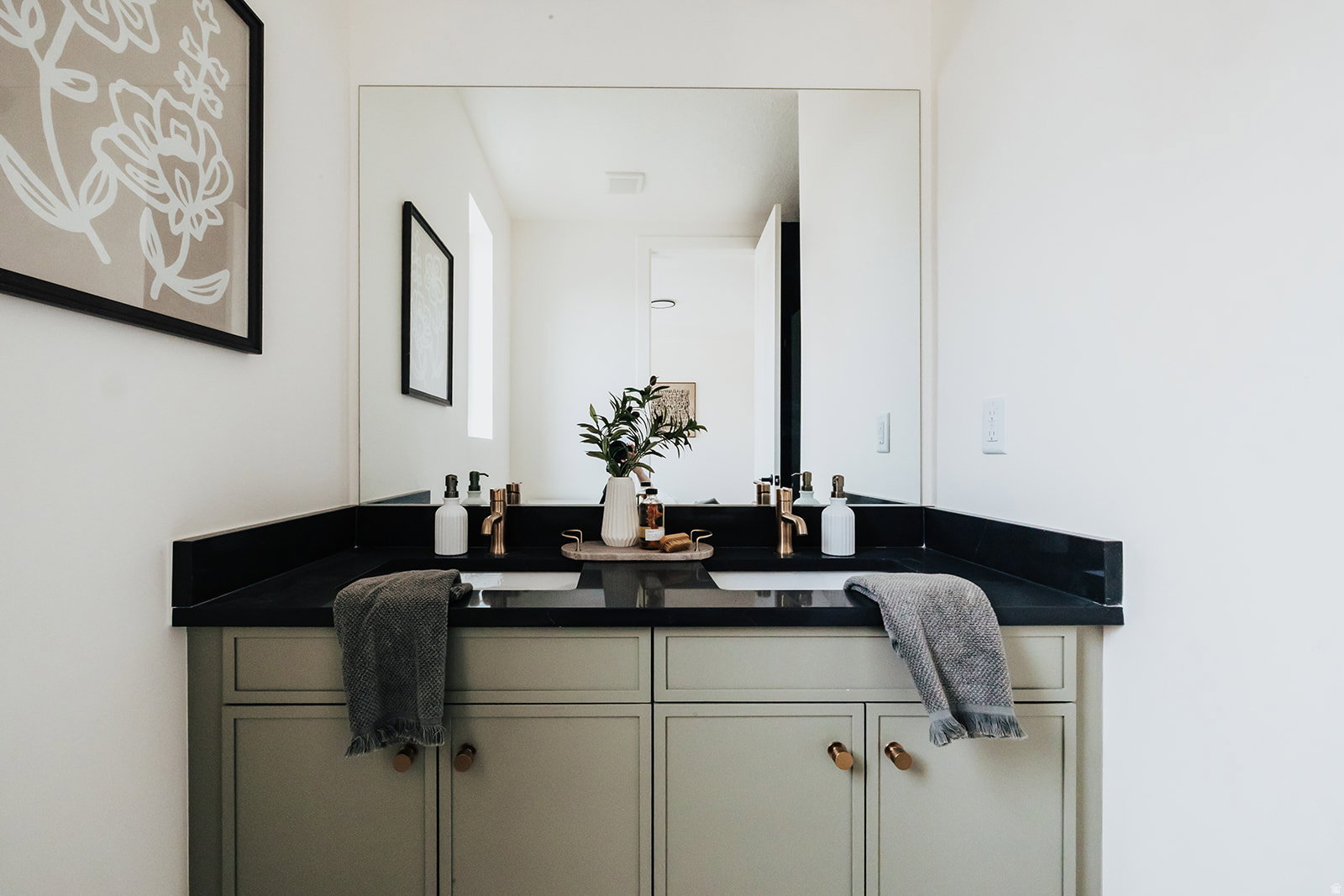 Double vanity featuring a black countertop, dual undermount sinks, and matte gold-finish fixtures