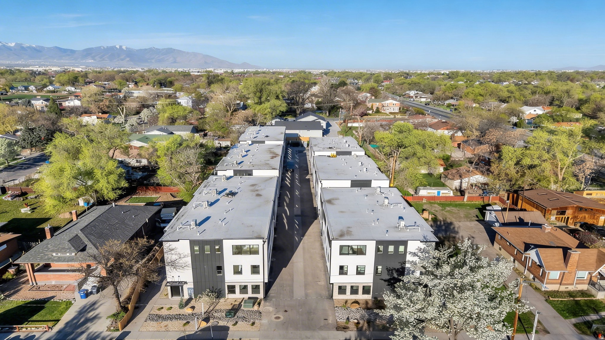 Modern multi-story residential buildings featuring white and dark gray facades with multiple window configurations