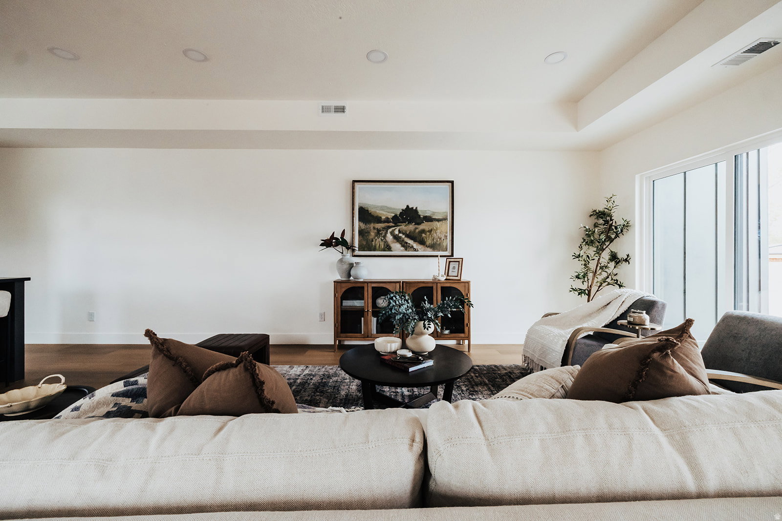 Spacious living area featuring light-toned walls, recessed lighting, wood-finish flooring, and large sliding glass doors