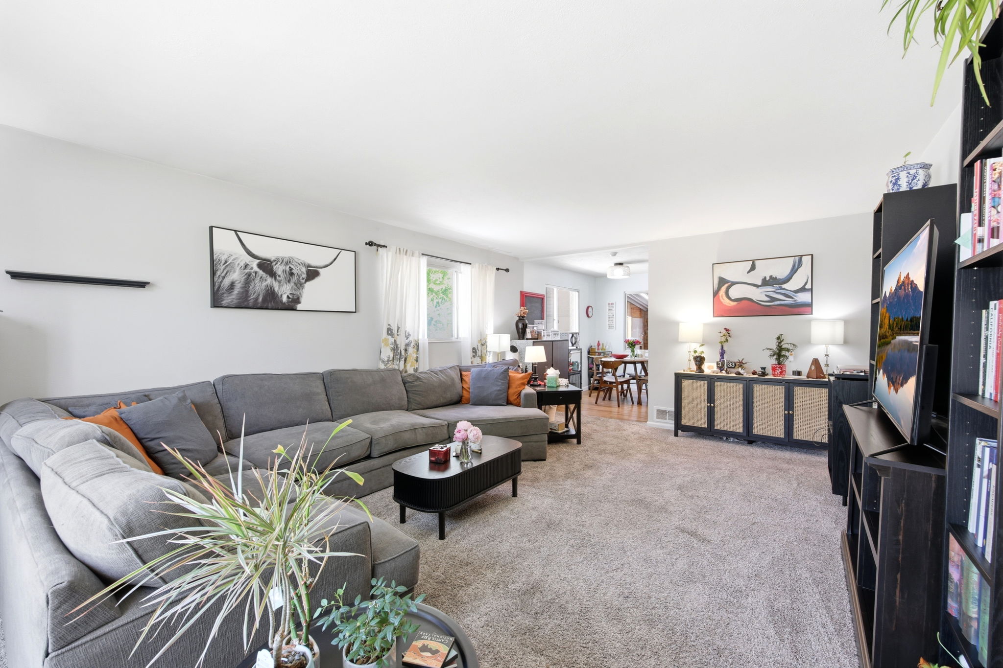 Spacious living area featuring light gray walls and plush carpeting