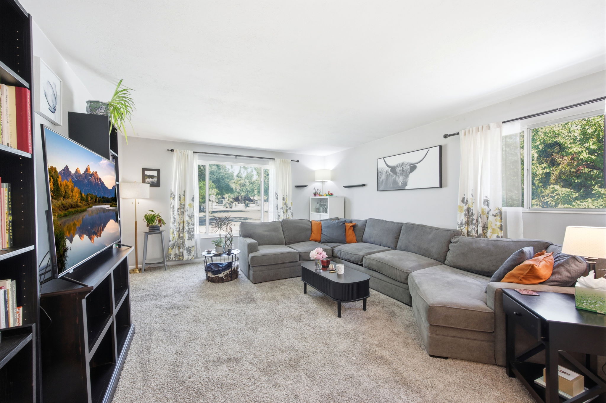 Spacious living area featuring light gray wall paint and light gray carpeting
