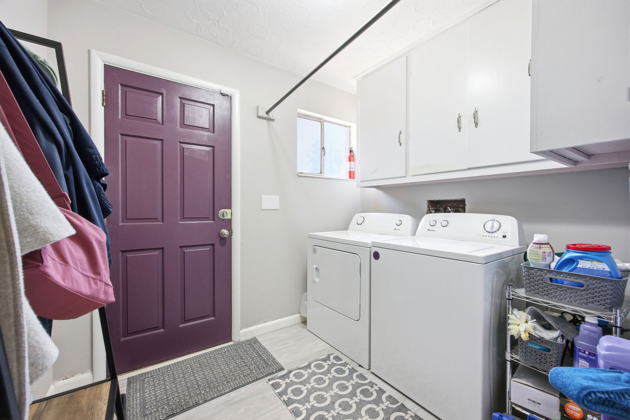 Dedicated laundry area featuring a panel door, overhead cabinetry, and light wood-finish flooring