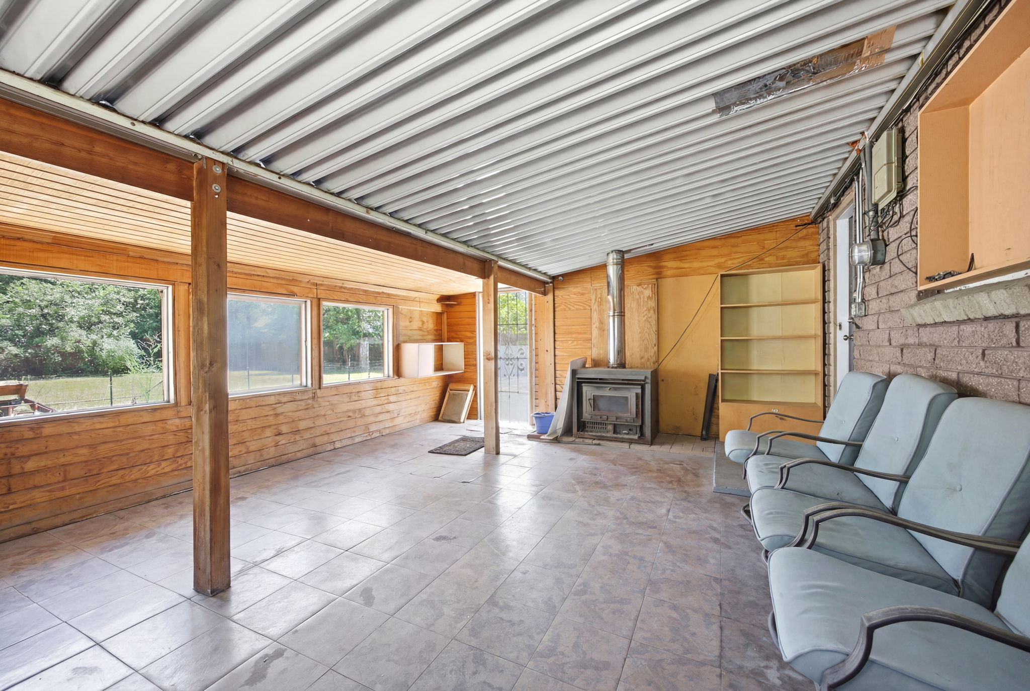 Spacious covered patio featuring a metal roof, wood-paneled walls, and tile flooring