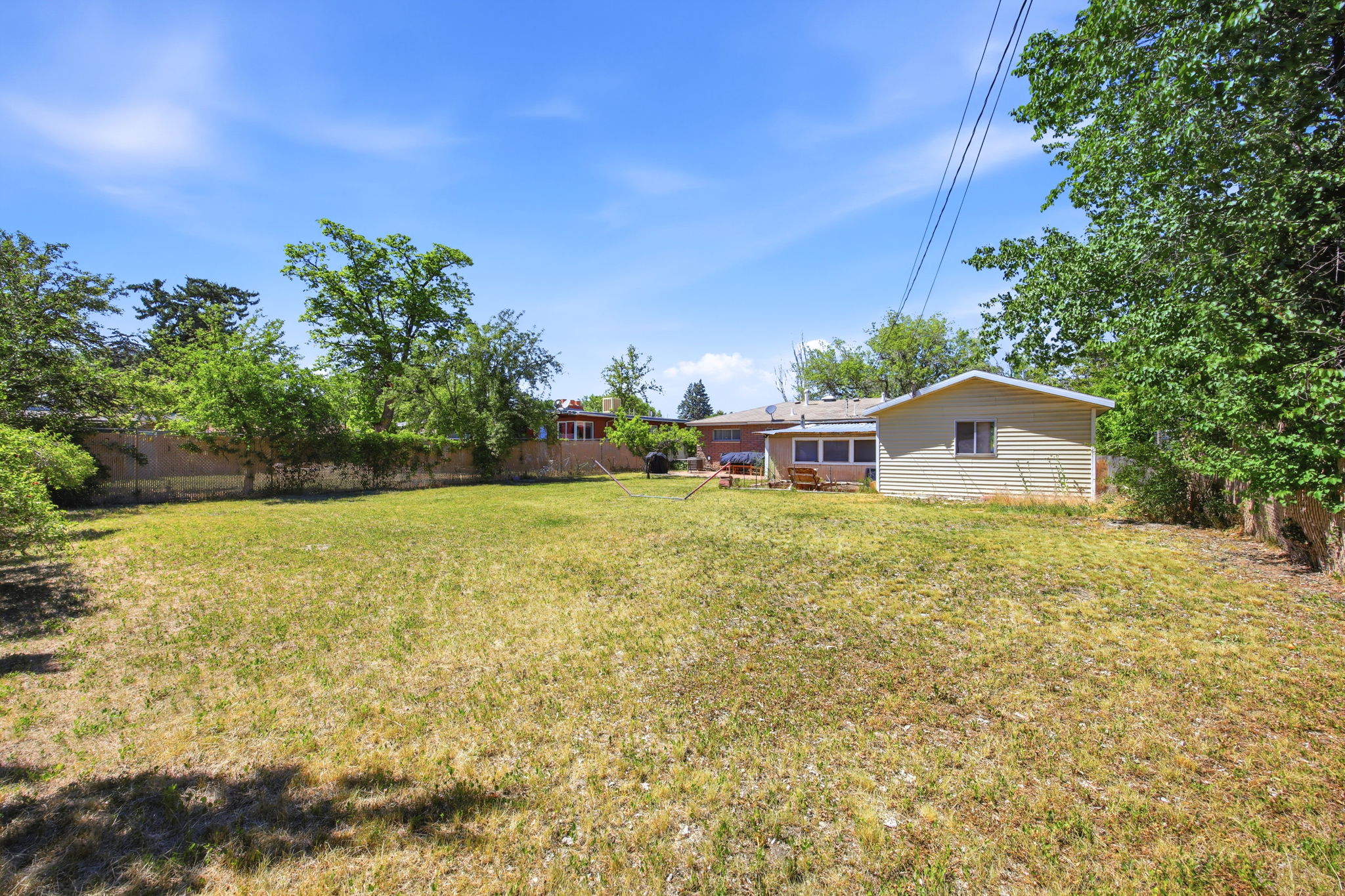 Expansive rear yard featuring natural grass and mature perimeter trees