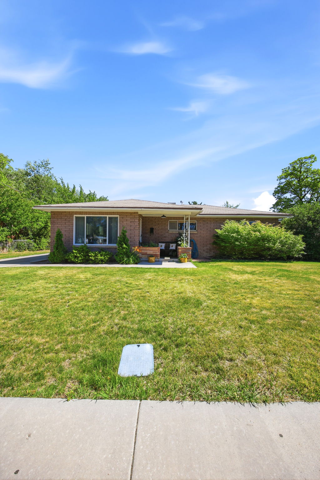 Brick ranch-style residence featuring a prominent front lawn