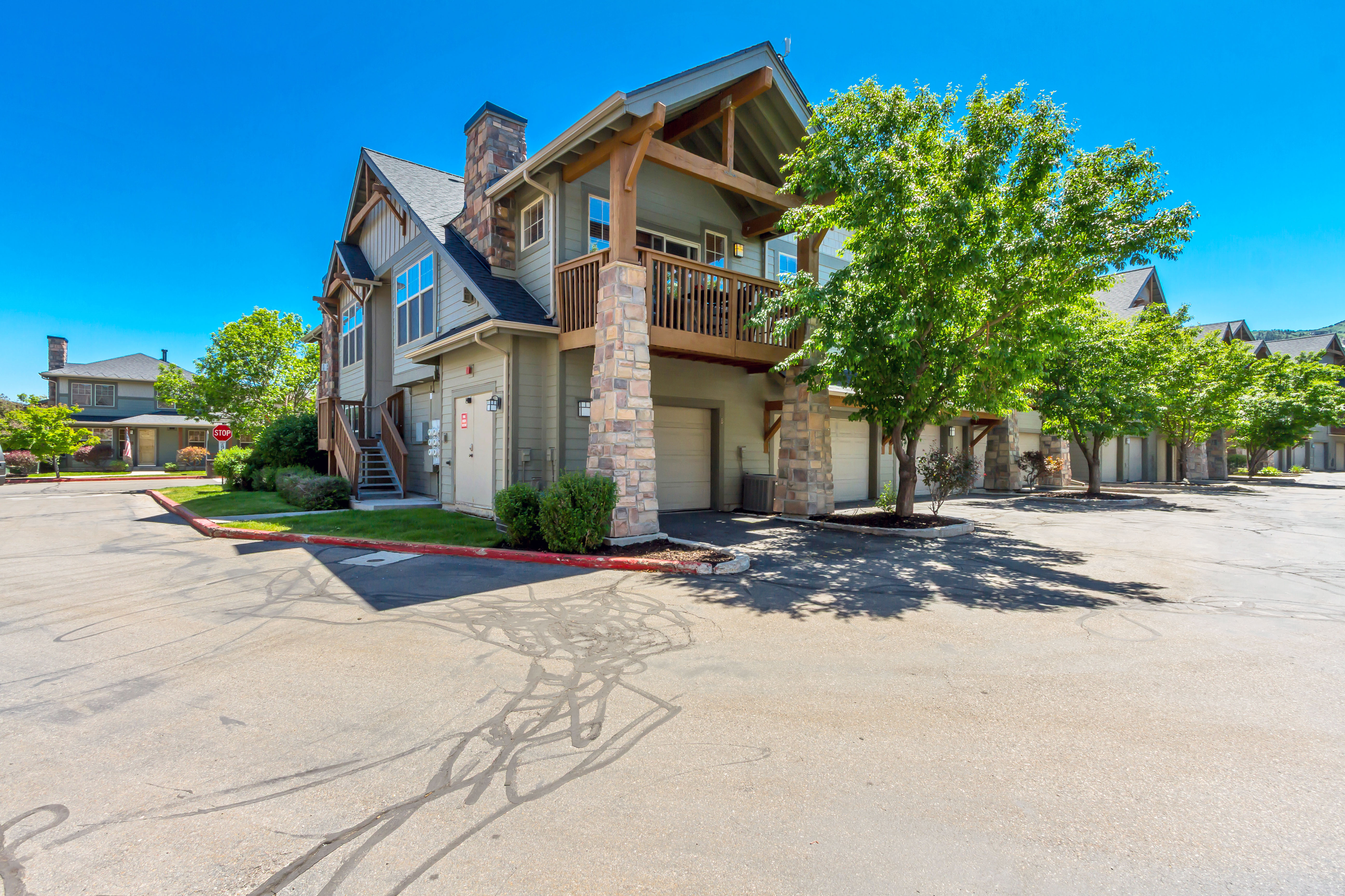 Exterior featuring a stone and wood-frame facade, multiple garage doors, and an upper-level balcony with wood railings