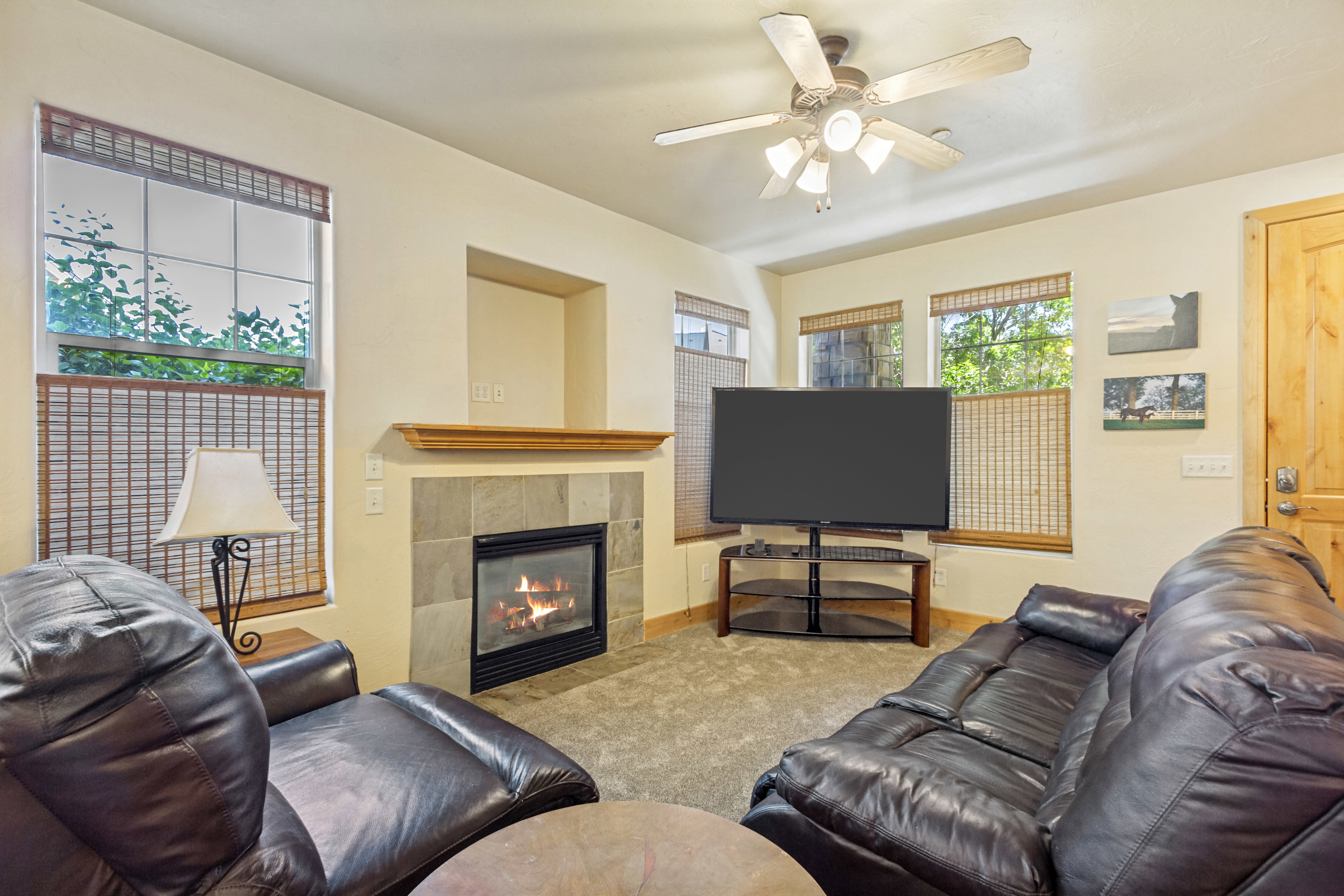 Living area featuring a tiled fireplace with a wood mantle, carpet flooring, and a ceiling fan with integrated lighting