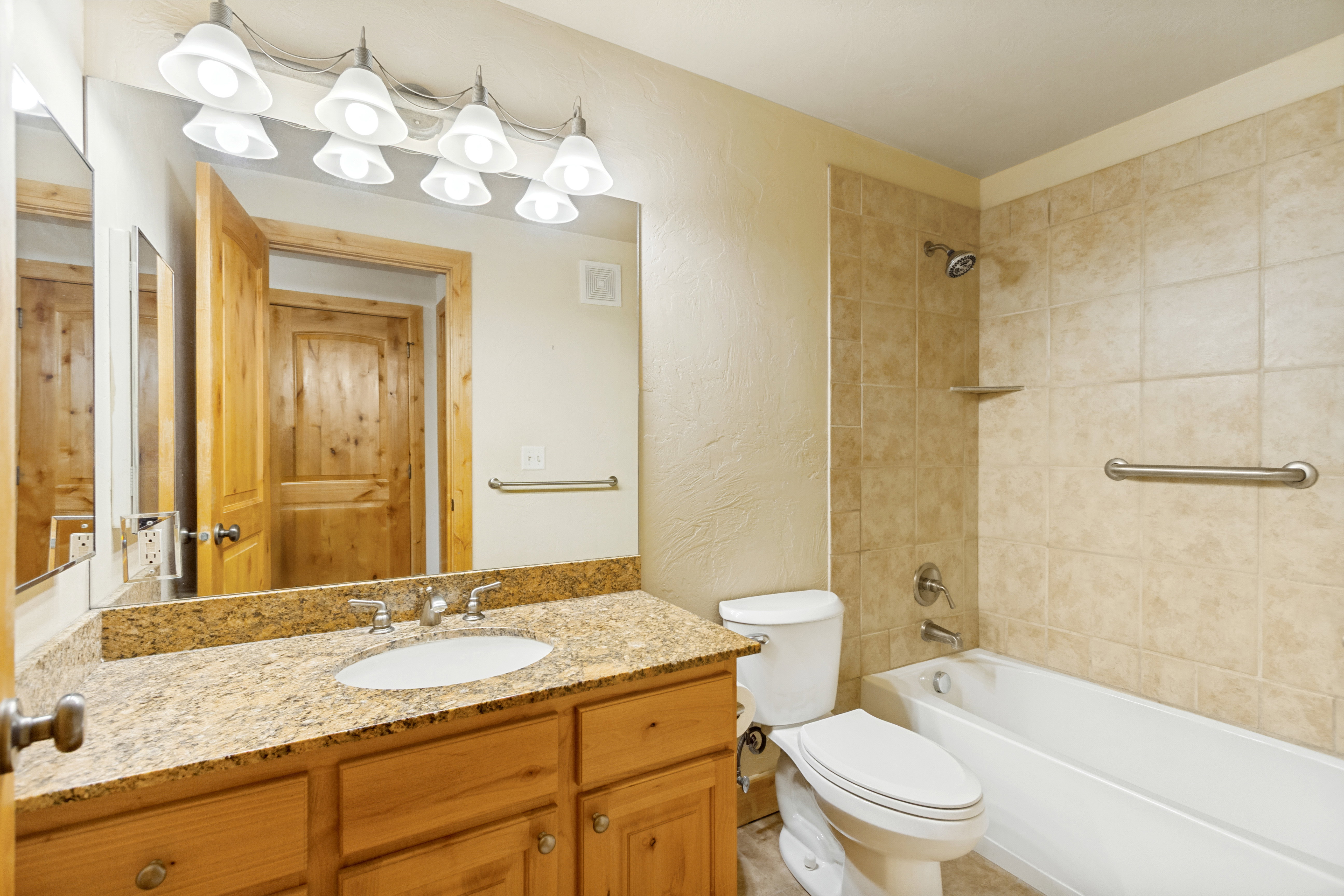 Bathroom featuring a light-toned vanity with a granite-style countertop, undermount sink, and brushed nickel fixtures
