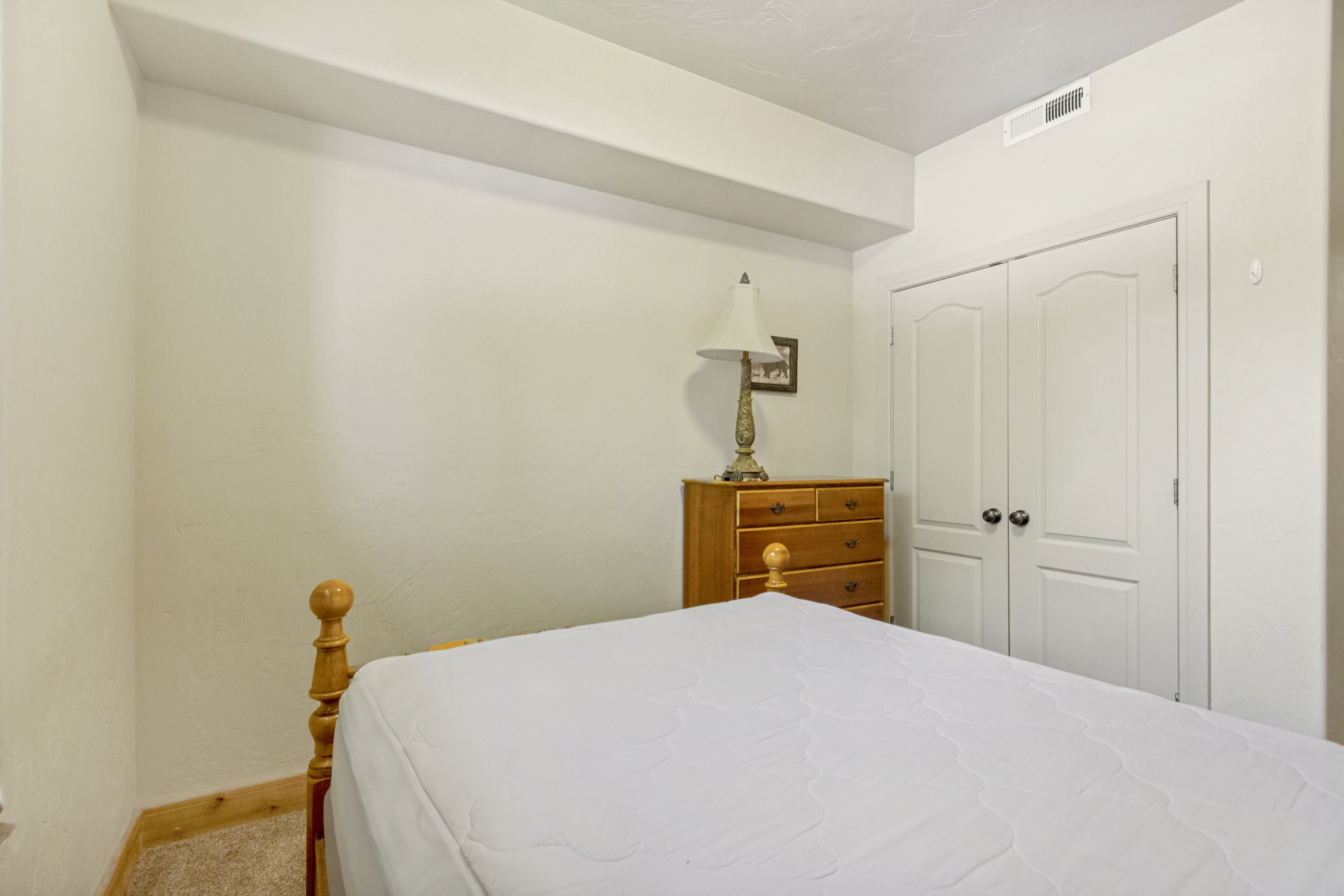 Room featuring neutral wall tones, carpeted flooring, white trim, and a double-door closet with arch paneling