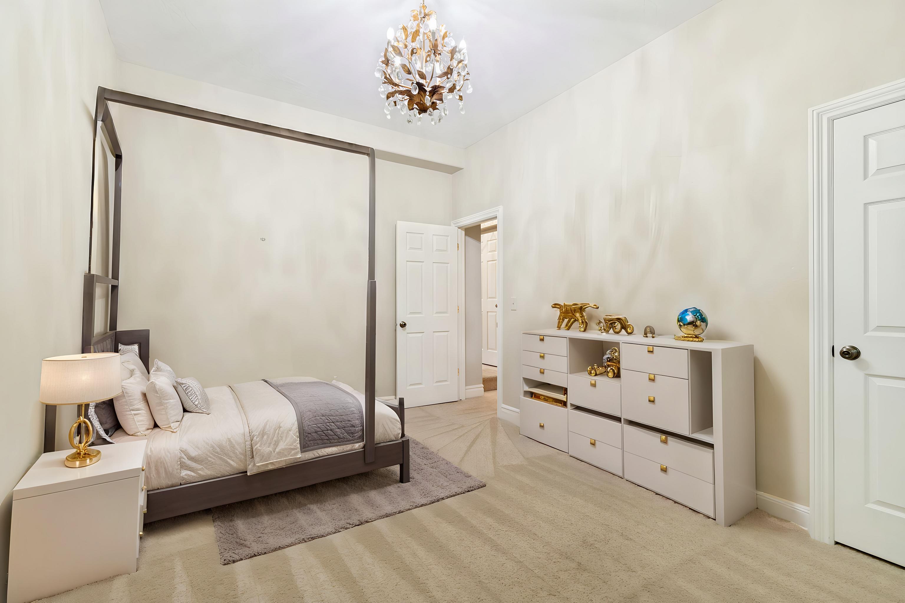 Light-toned walls complement plush carpet flooring in this room featuring a crystal chandelier