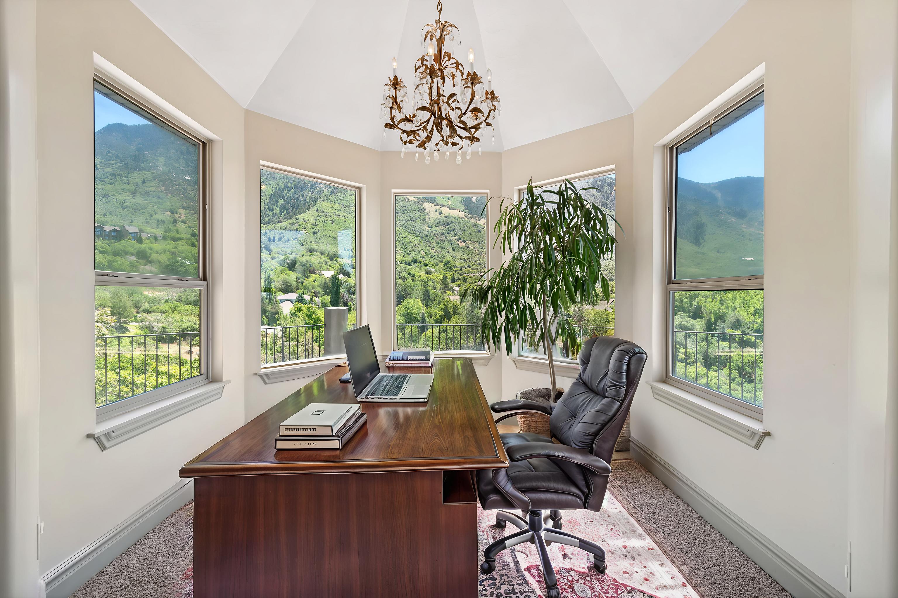 Octagonal room with multiple windows overlooking natural scenery, featuring a decorative chandelier and light-toned wall finishes