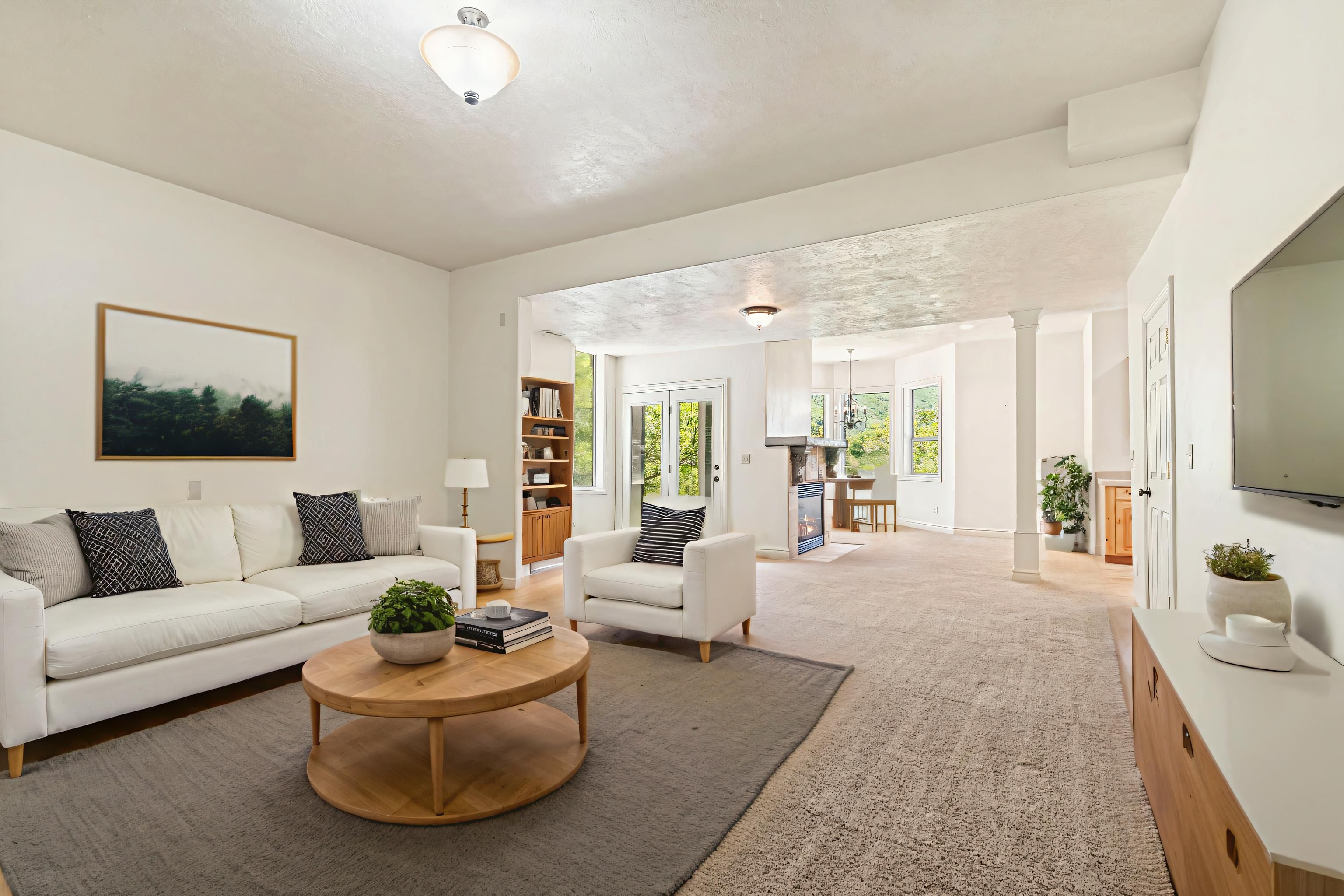 Spacious living area featuring light-toned walls, recessed lighting, and a neutral carpet