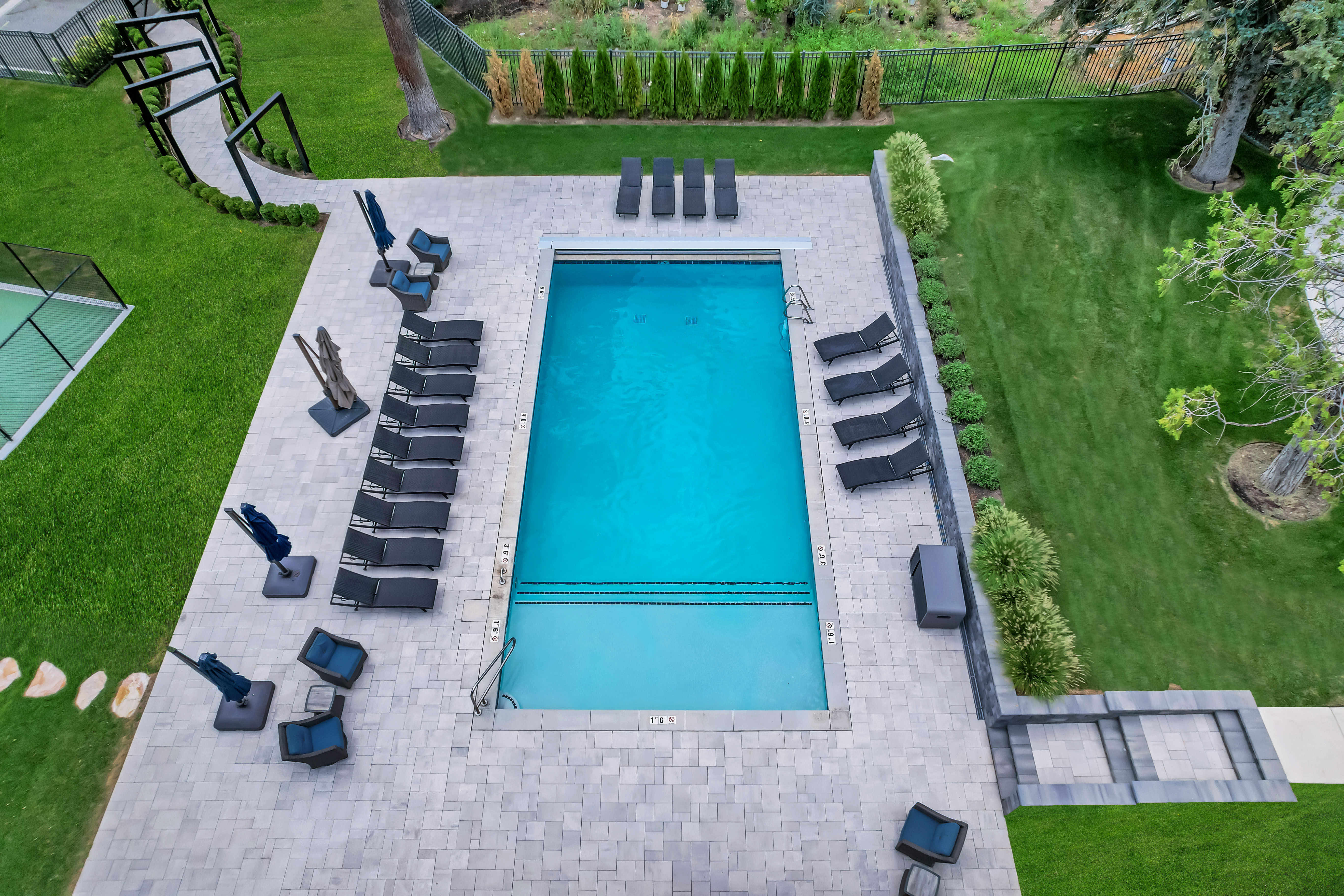 Rectangular swimming pool with integrated steps, surrounded by a light-toned paver patio