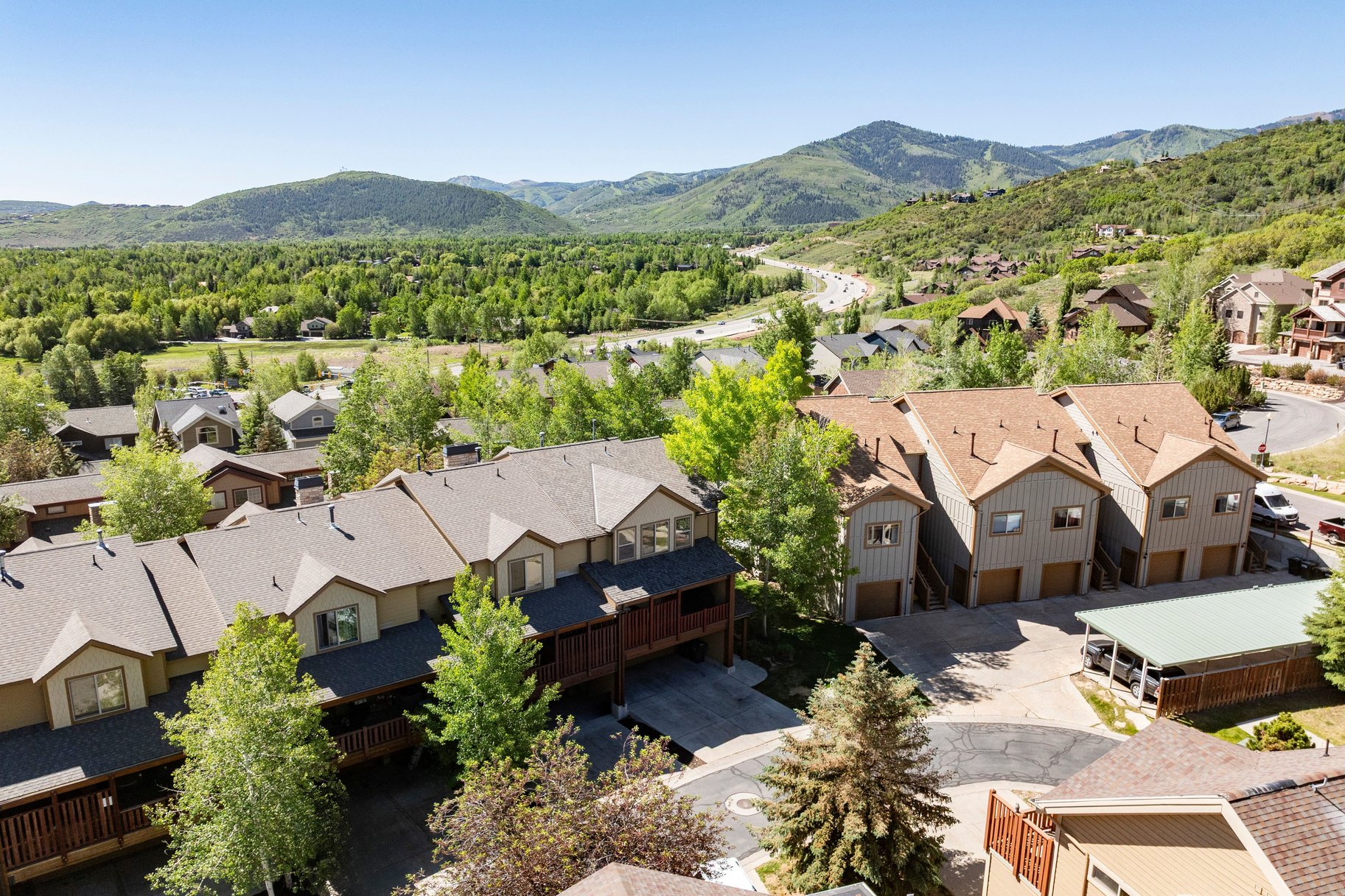 Townhome row featuring neutral-toned siding, gabled rooflines, and individual garage access