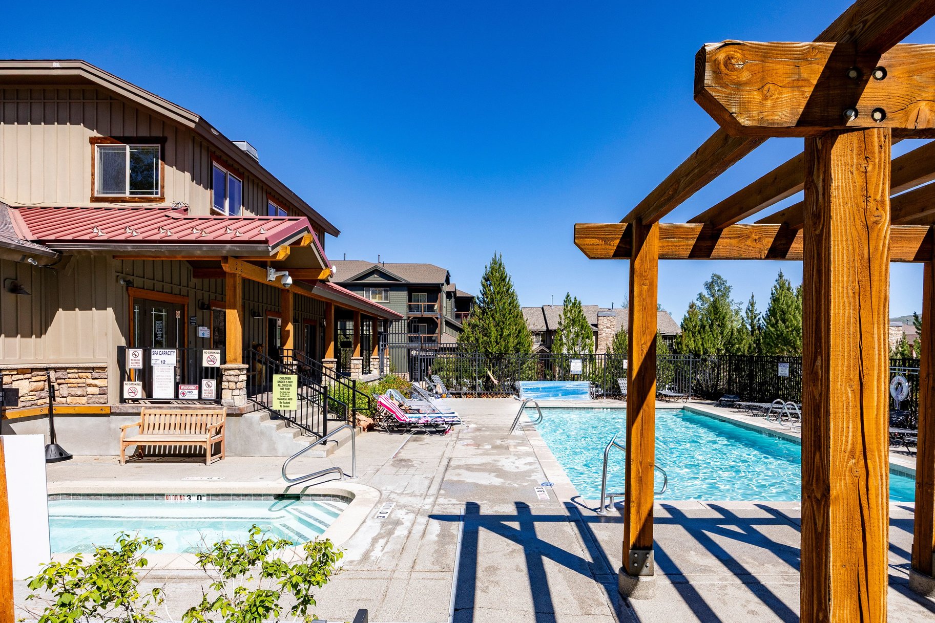 Outdoor amenity space featuring multiple swimming pools, a hot tub, and a decorative timber pergola