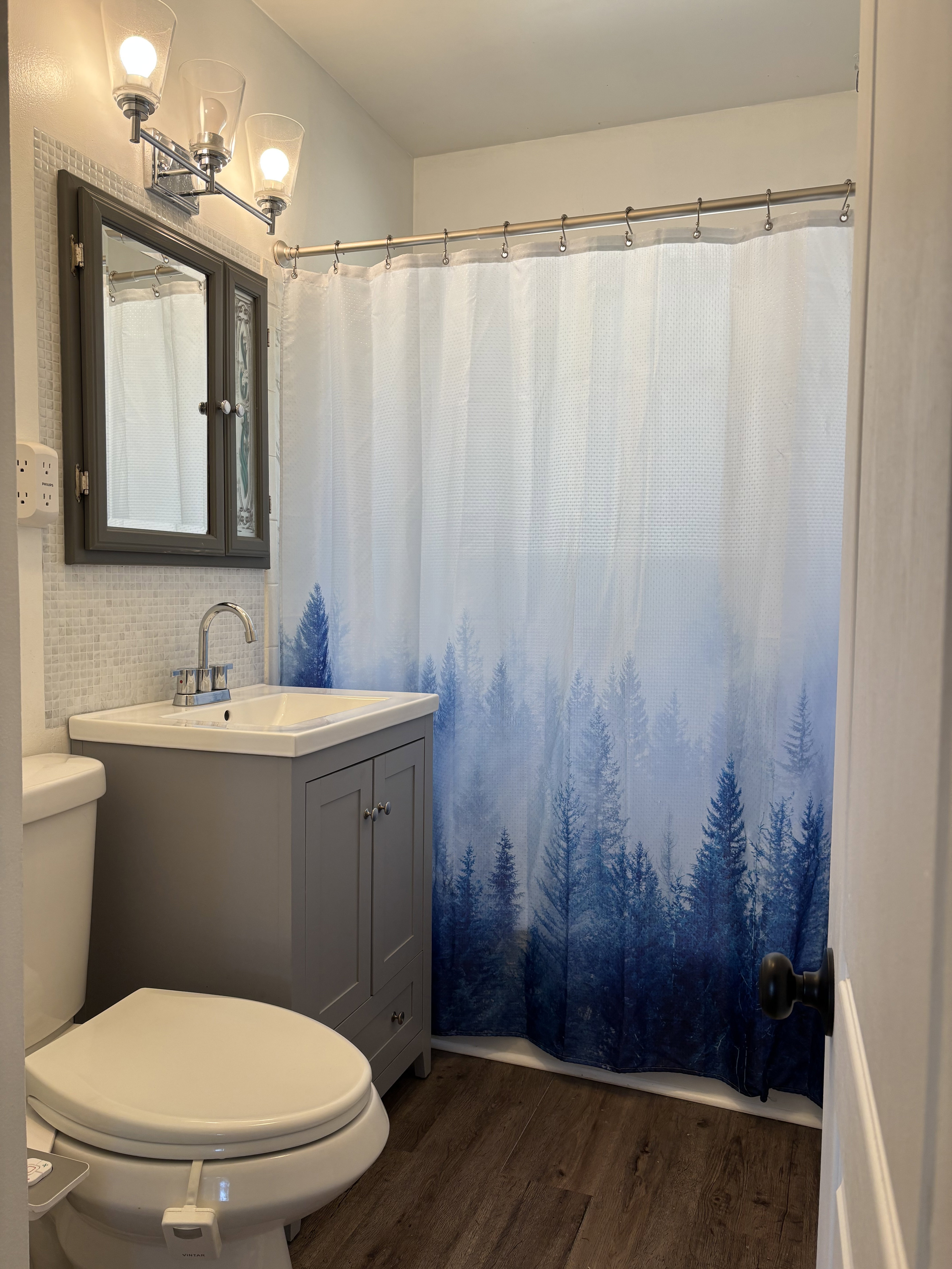 Bathroom featuring a contemporary gray vanity with an integrated sink, mosaic tile backsplash, and wood-finish flooring