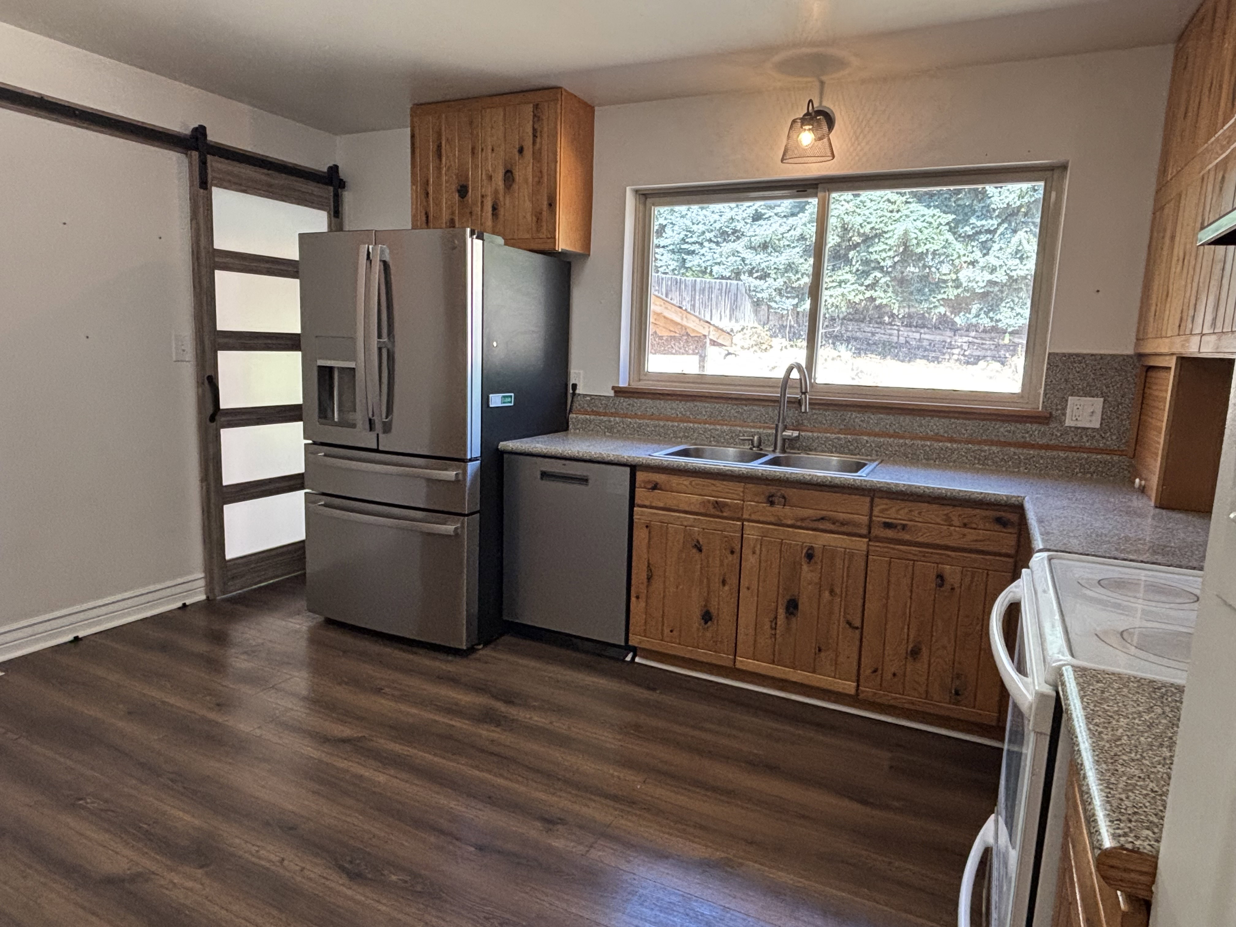 Kitchen featuring wood-finish flooring, natural wood cabinetry, stainless steel appliances, and a double basin sink