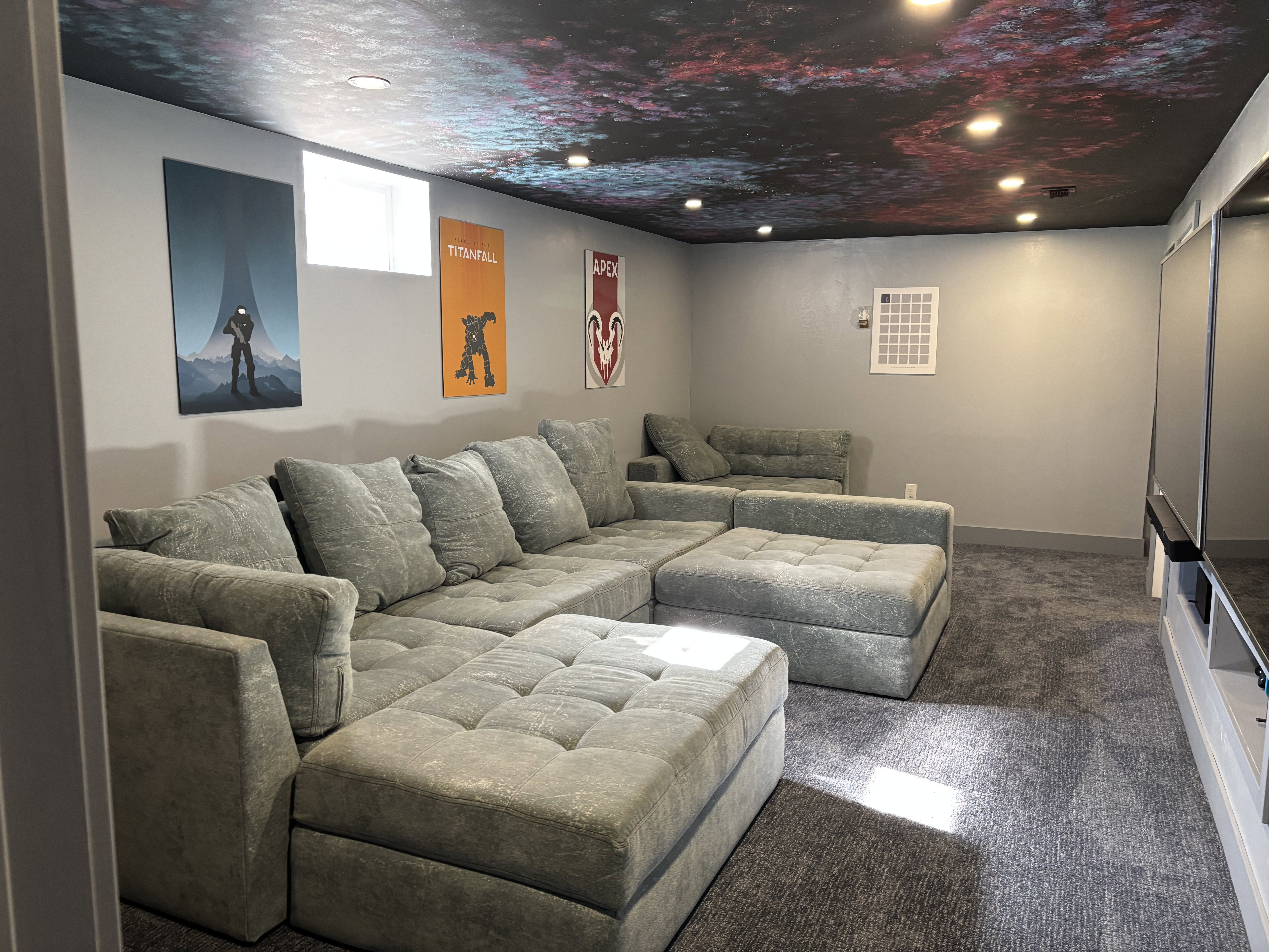 Recreation room featuring a distinctive patterned ceiling with recessed lighting, blue-gray carpeting, a window, and gray painted walls