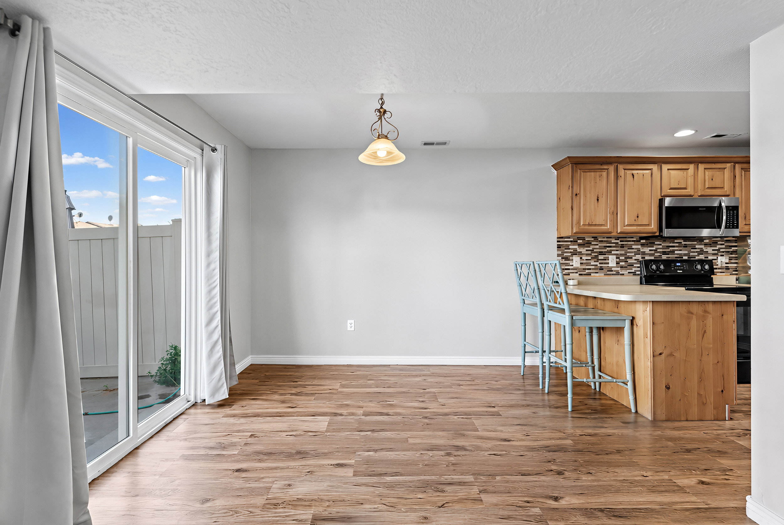 Open-concept living space featuring wood-finish flooring, a sliding glass door with exterior access, and a kitchen island with seating