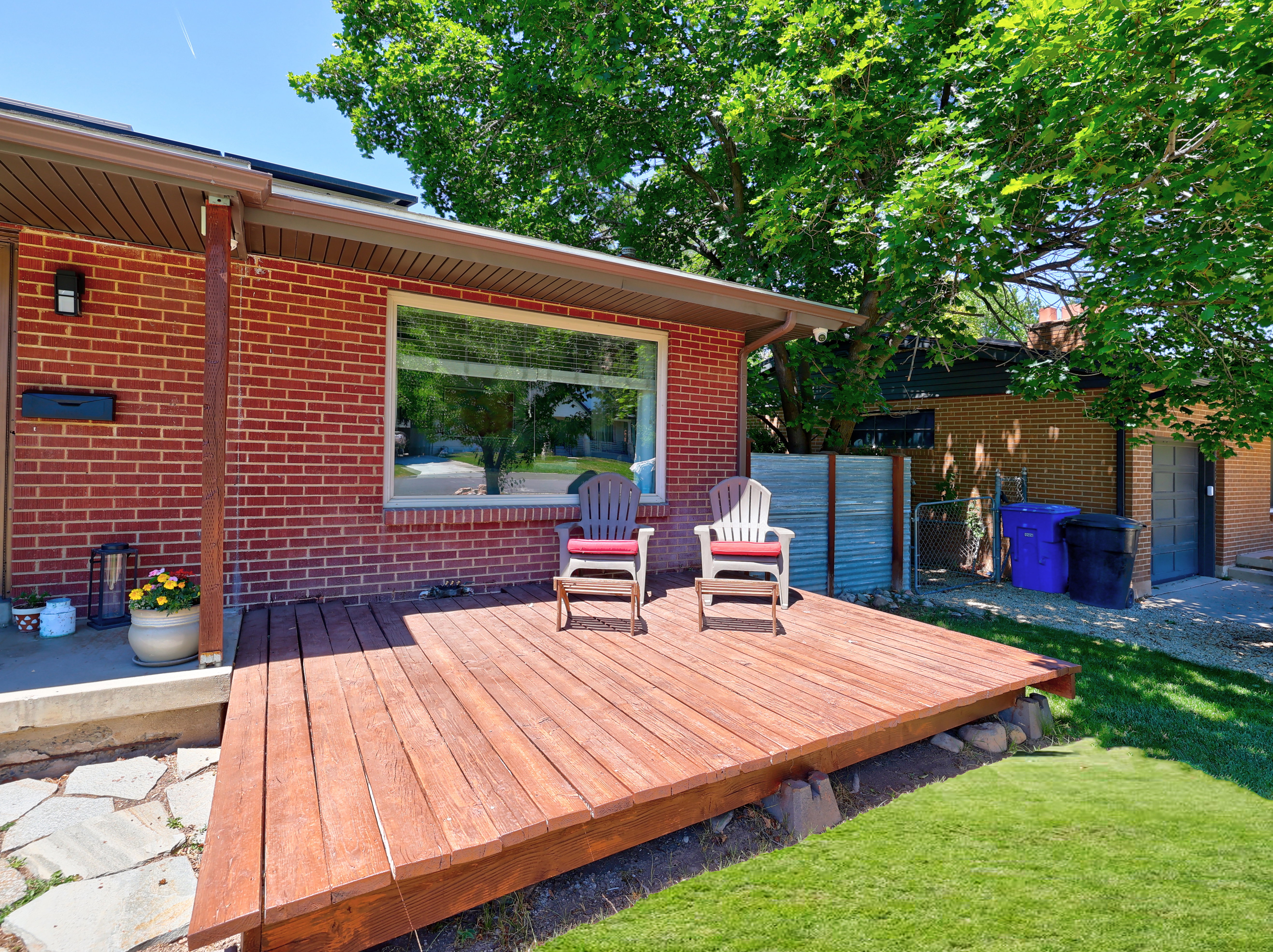 Brick exterior featuring a wood deck, large picture window, and a flagstone pathway