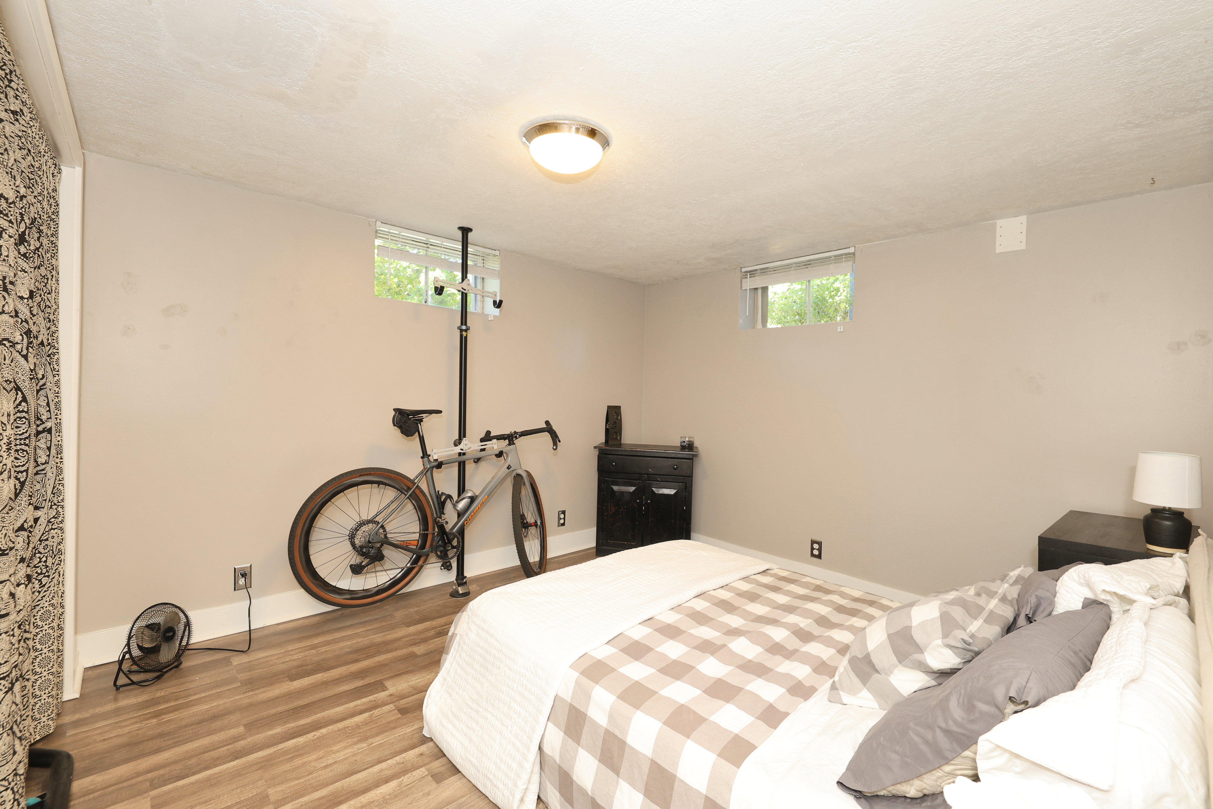 Lower-level room with wood-finish flooring, neutral wall paint, and two egress windows