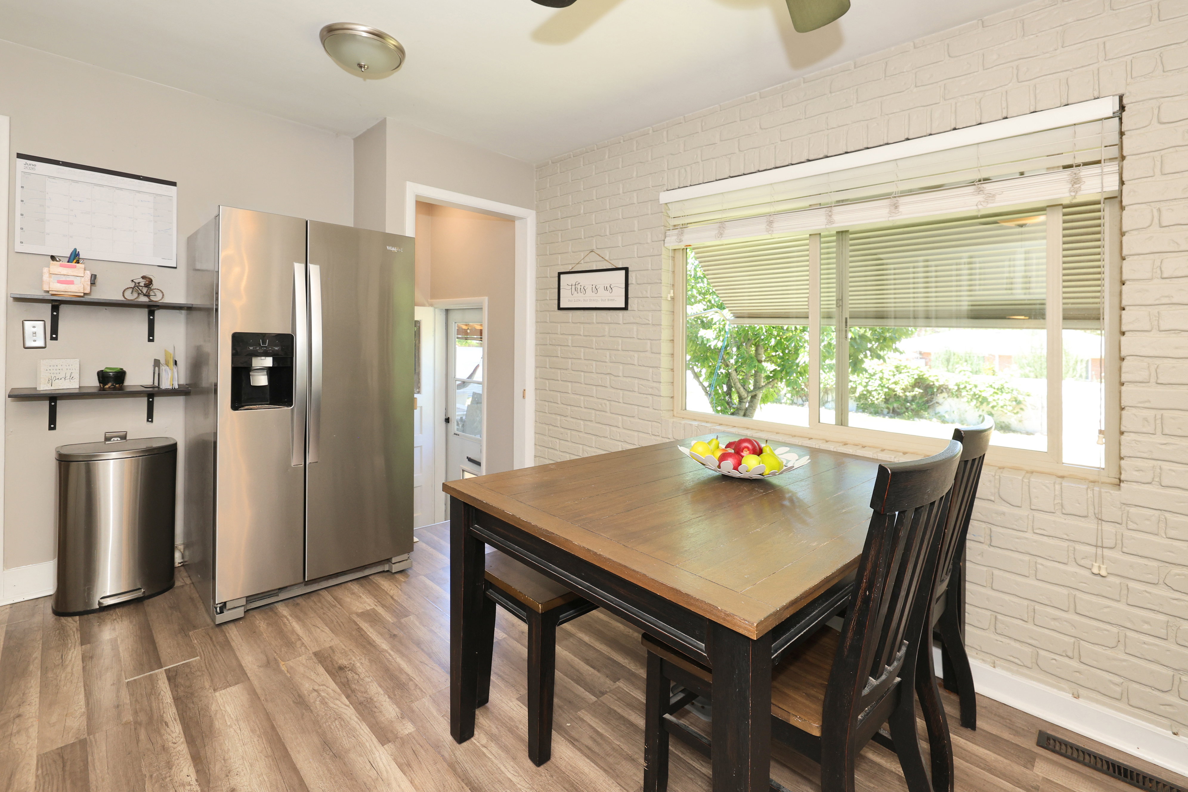 Kitchen space with wood-finish flooring, a stainless steel side-by-side refrigerator, and open shelving