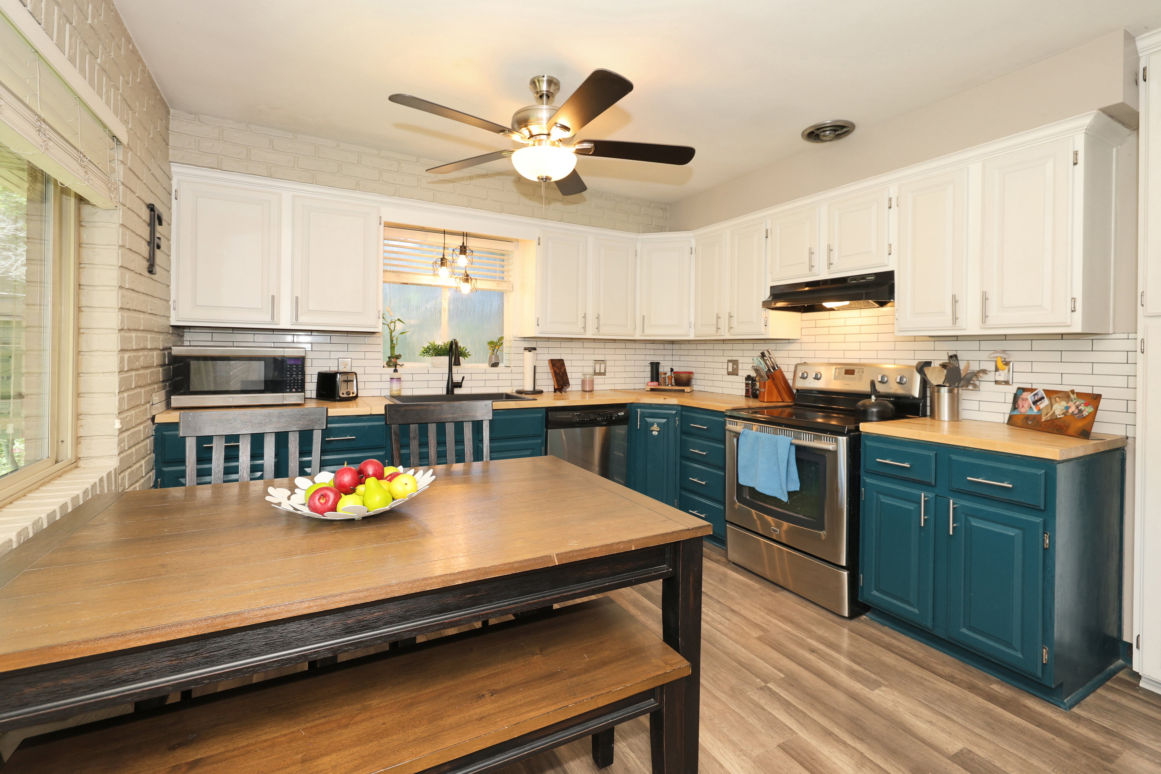 Kitchen featuring two-tone cabinetry, stainless steel appliances, a subway tile backsplash, and light wood-finish flooring