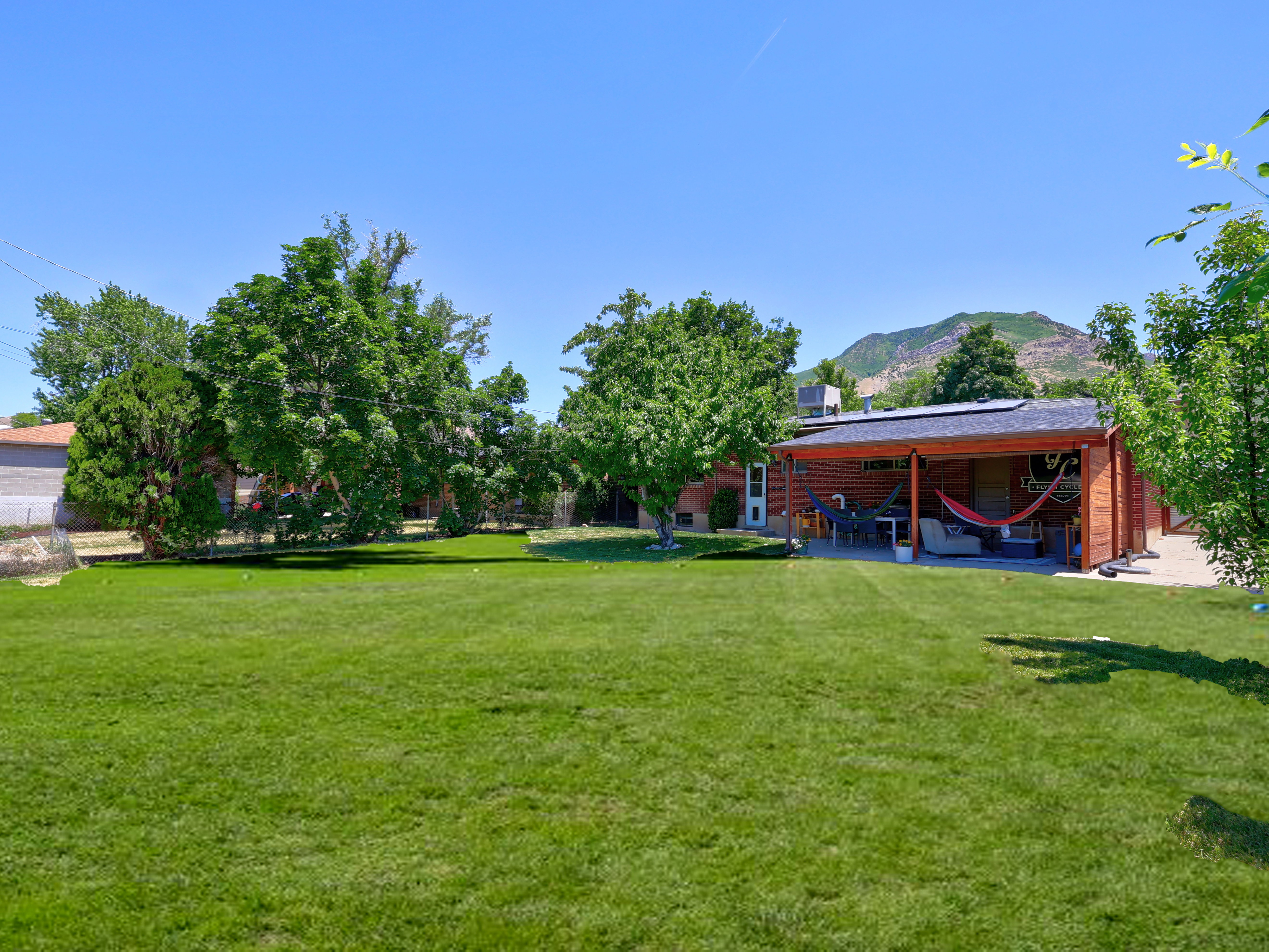 Expansive green lawn with mature trees and a mountain backdrop