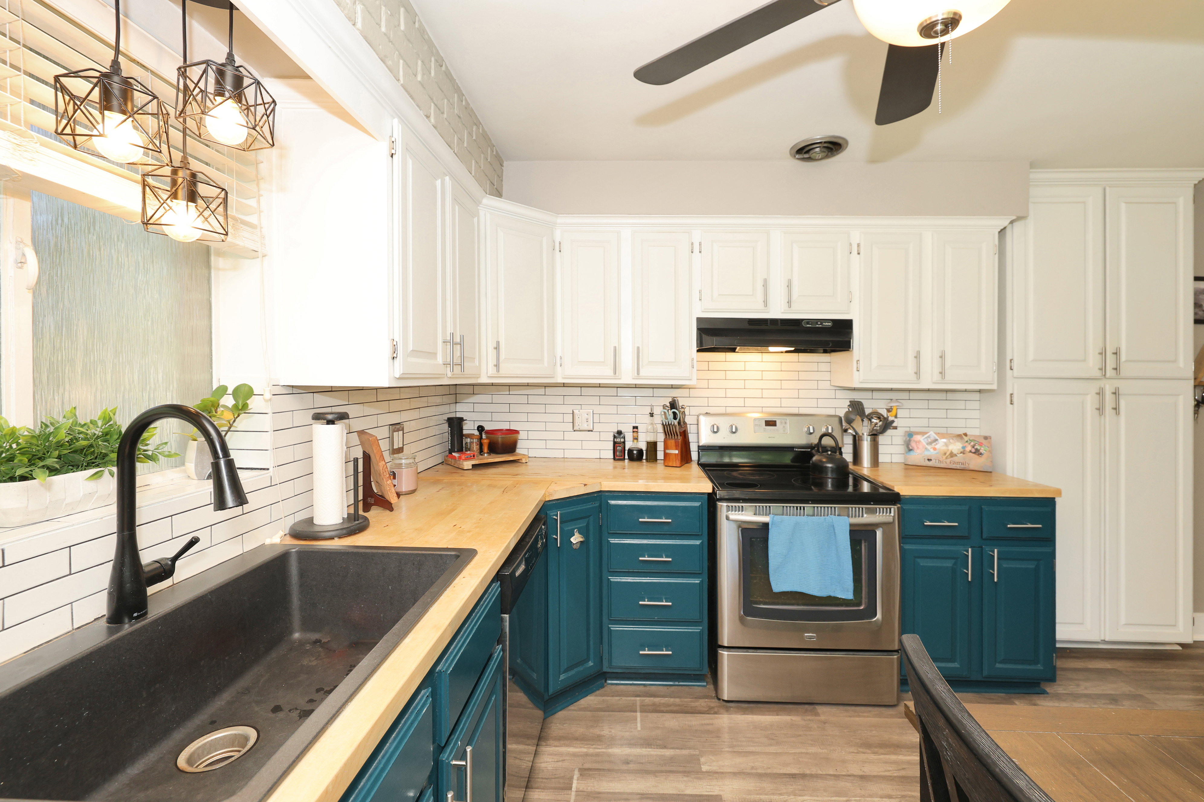 Kitchen with two-tone cabinetry featuring white upper cabinets and teal lower cabinets