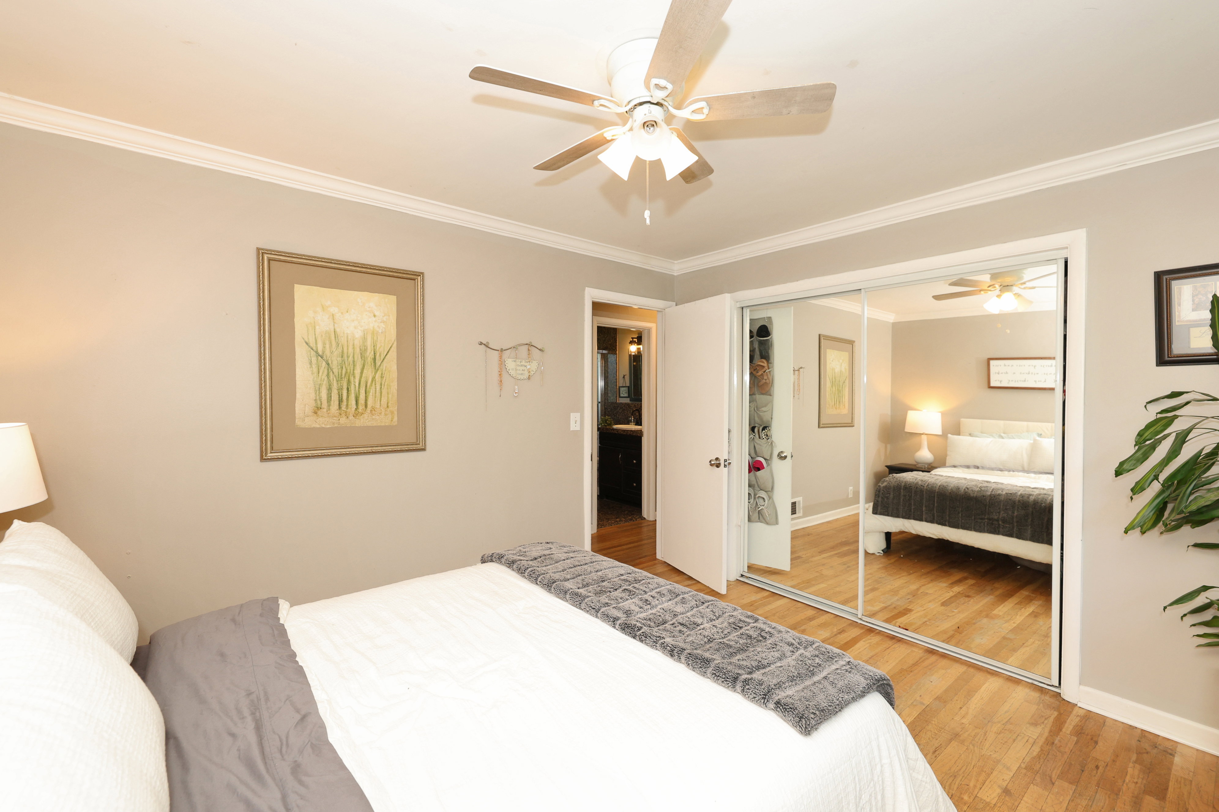 Bedroom featuring wood-finish flooring, a ceiling fan with integrated lighting, and crown molding