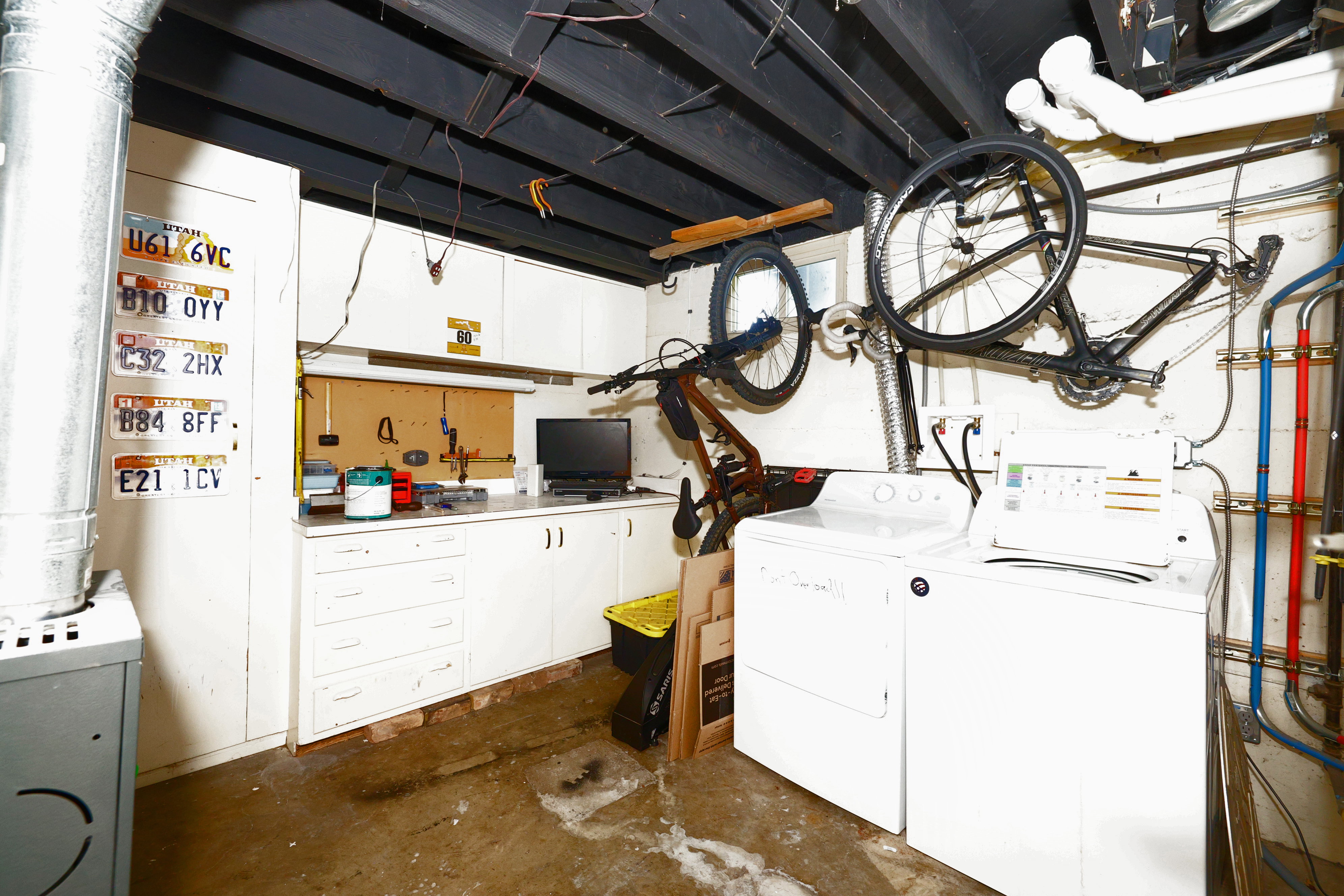 Utility area featuring a washer and dryer, built-in cabinetry with a countertop, exposed ceiling joists, and visible plumbing