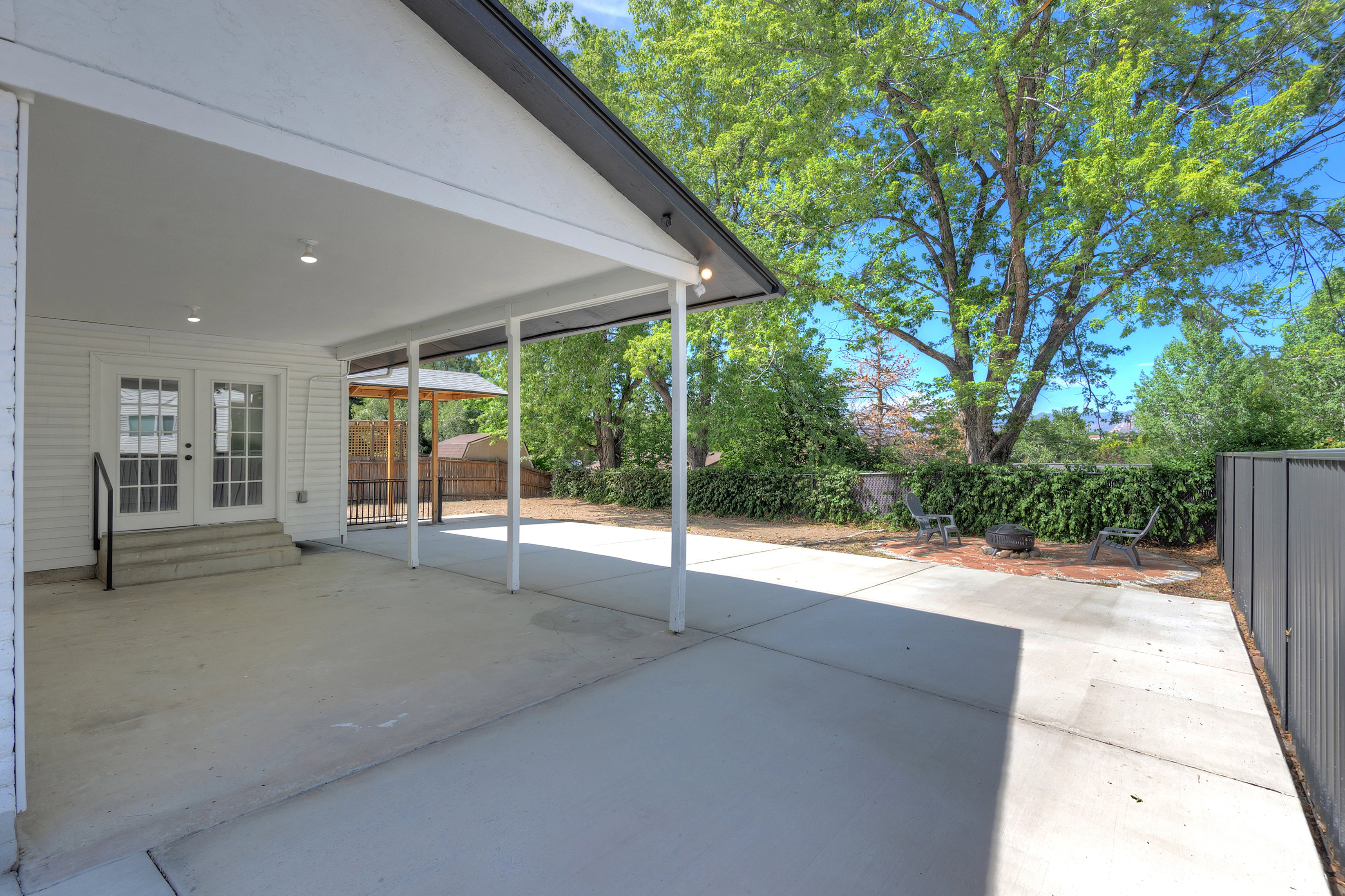 Covered patio with recessed lighting and concrete flooring, featuring French doors with transom windows