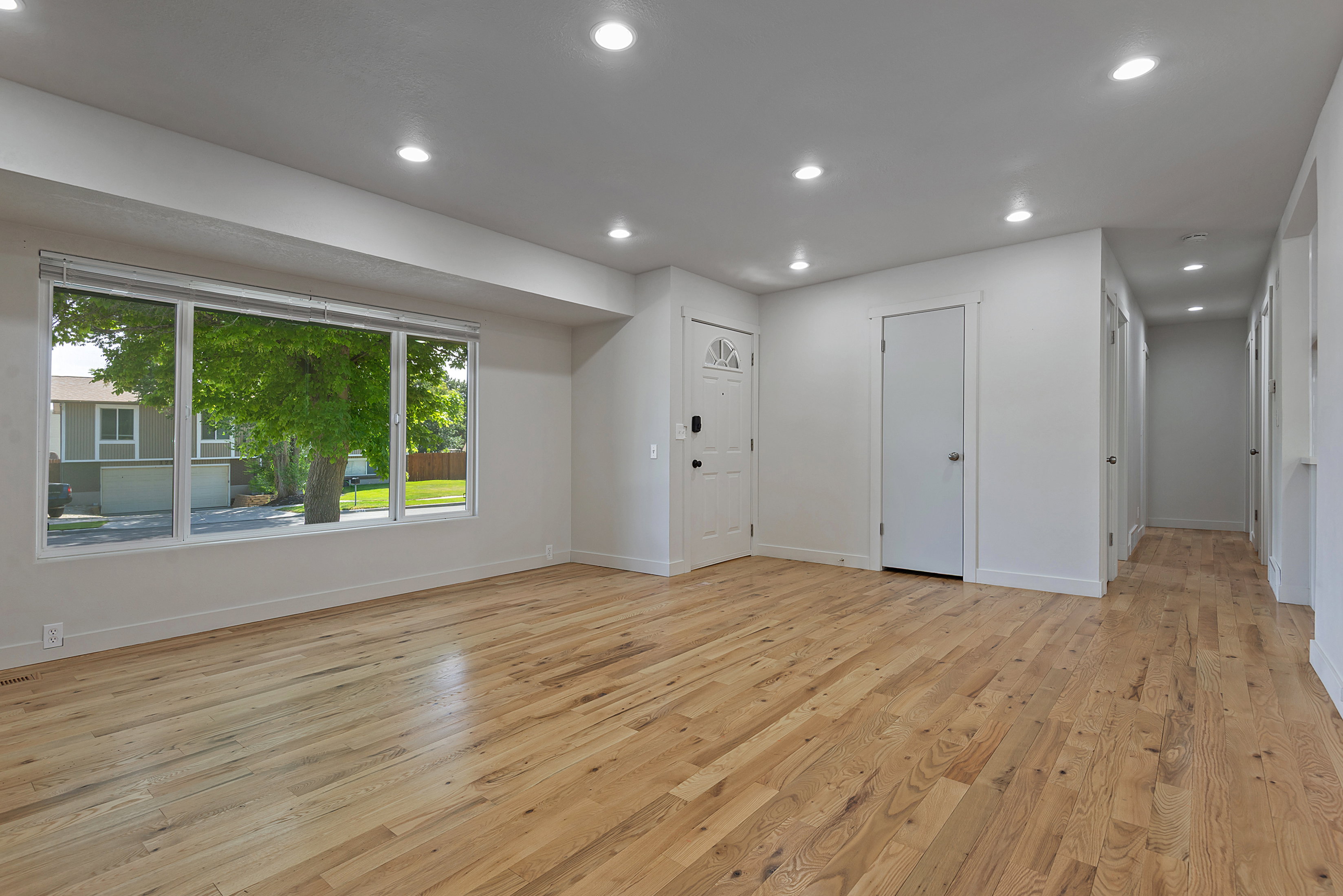 Spacious living area featuring wood-finish flooring, recessed lighting, and a large multi-pane window