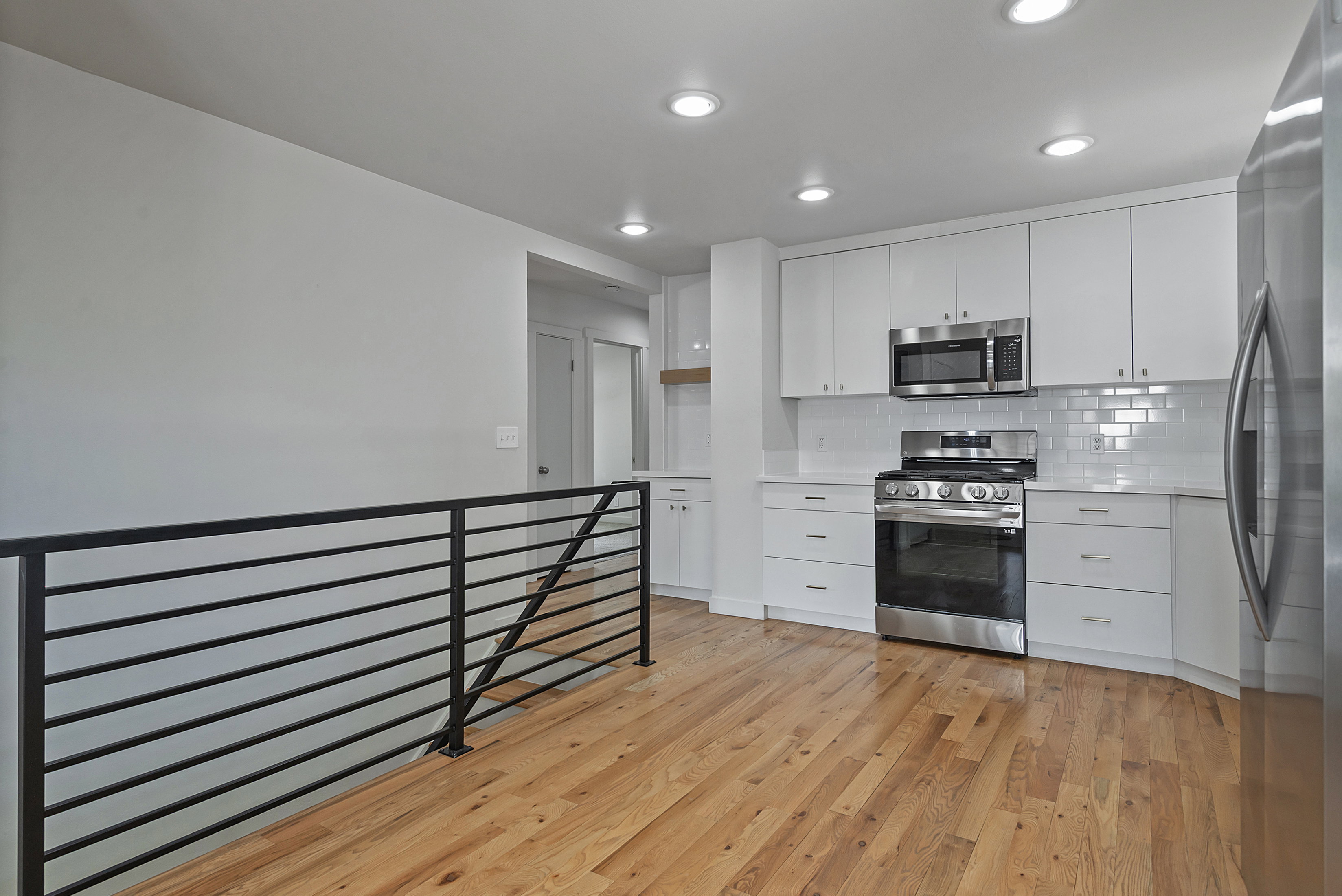 Modern kitchen featuring white cabinetry, subway tile backsplash, stainless steel appliances, and a gas range