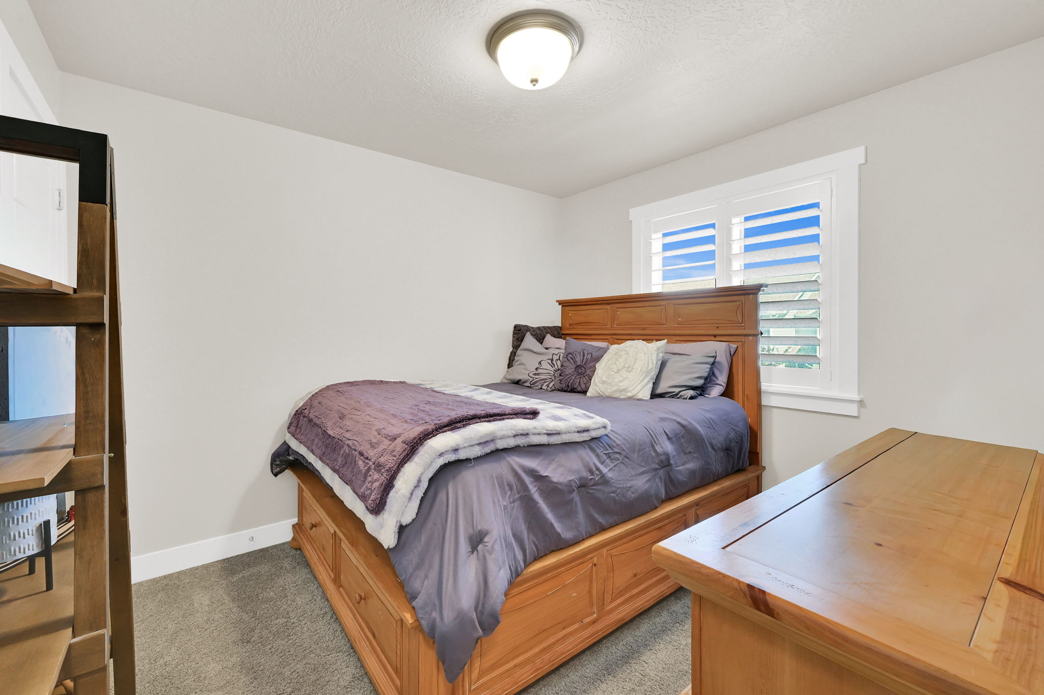 Bedroom 3- featuring a   window with plantation shutters, ceiling fan with integrated lighting, carpet and light-toned wall paint