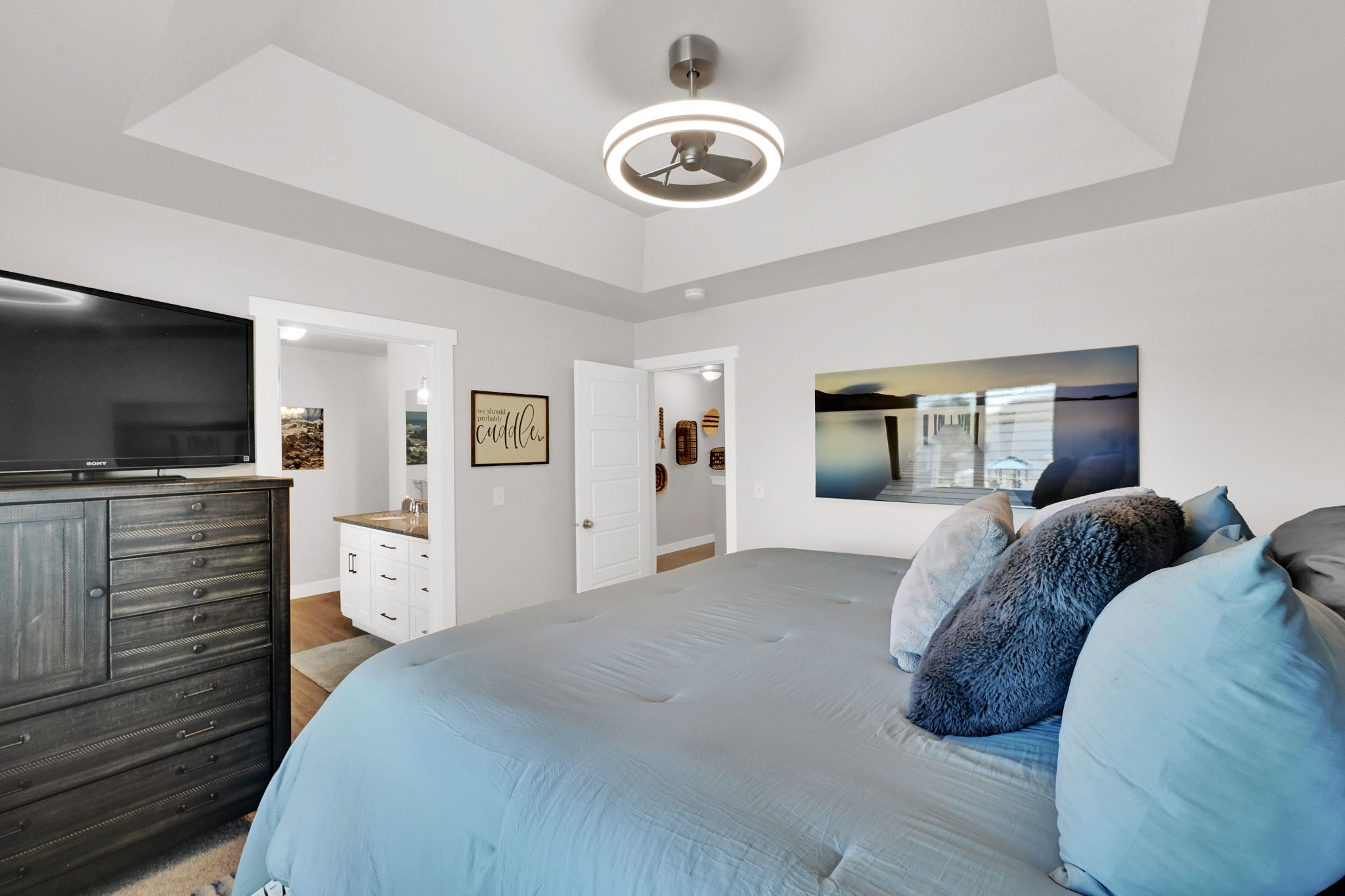 Primary Bedroom- featuring primary en suite, walk in closet, window with plantation shutters, ceiling fan with integrated lighting, carpet, and light-toned wall paint