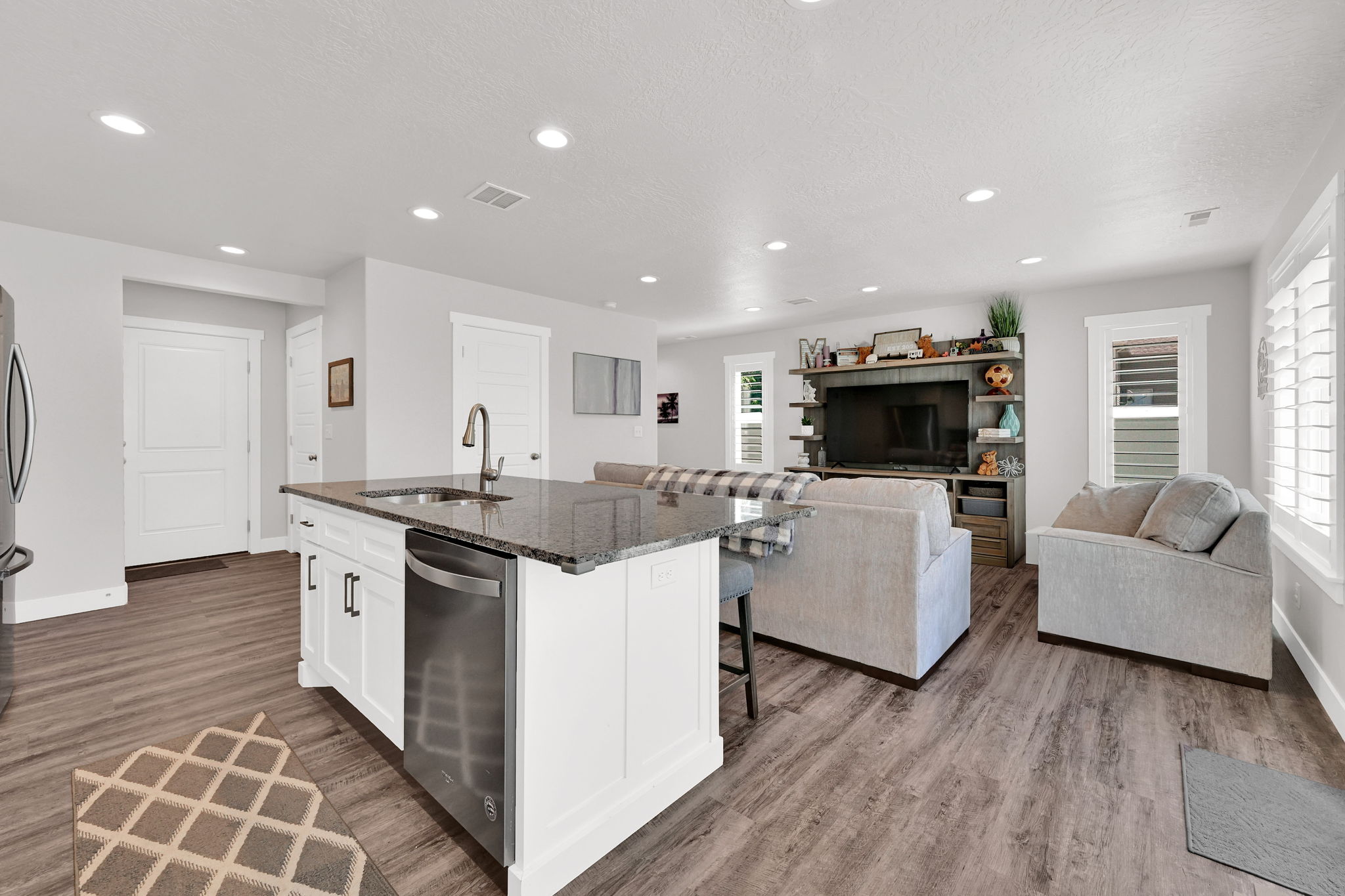 Open-concept living space/kitchen  featuring LVP flooring, recessed lighting, and white plantation shutters