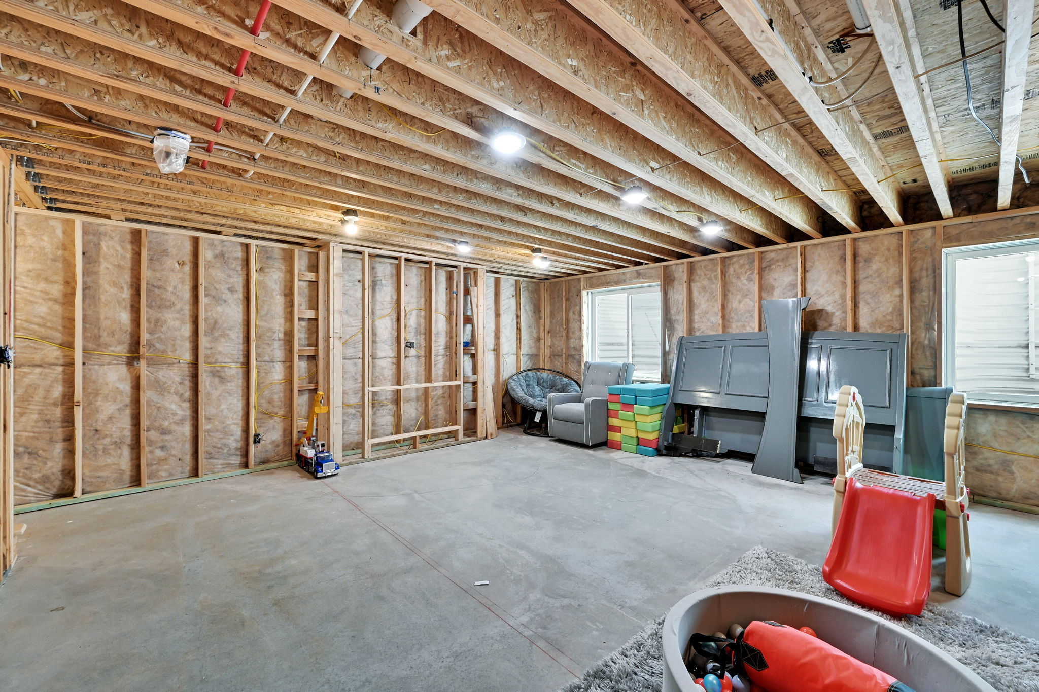 Unfinished basement space featuring framing, concrete flooring, and multiple windows for natural light