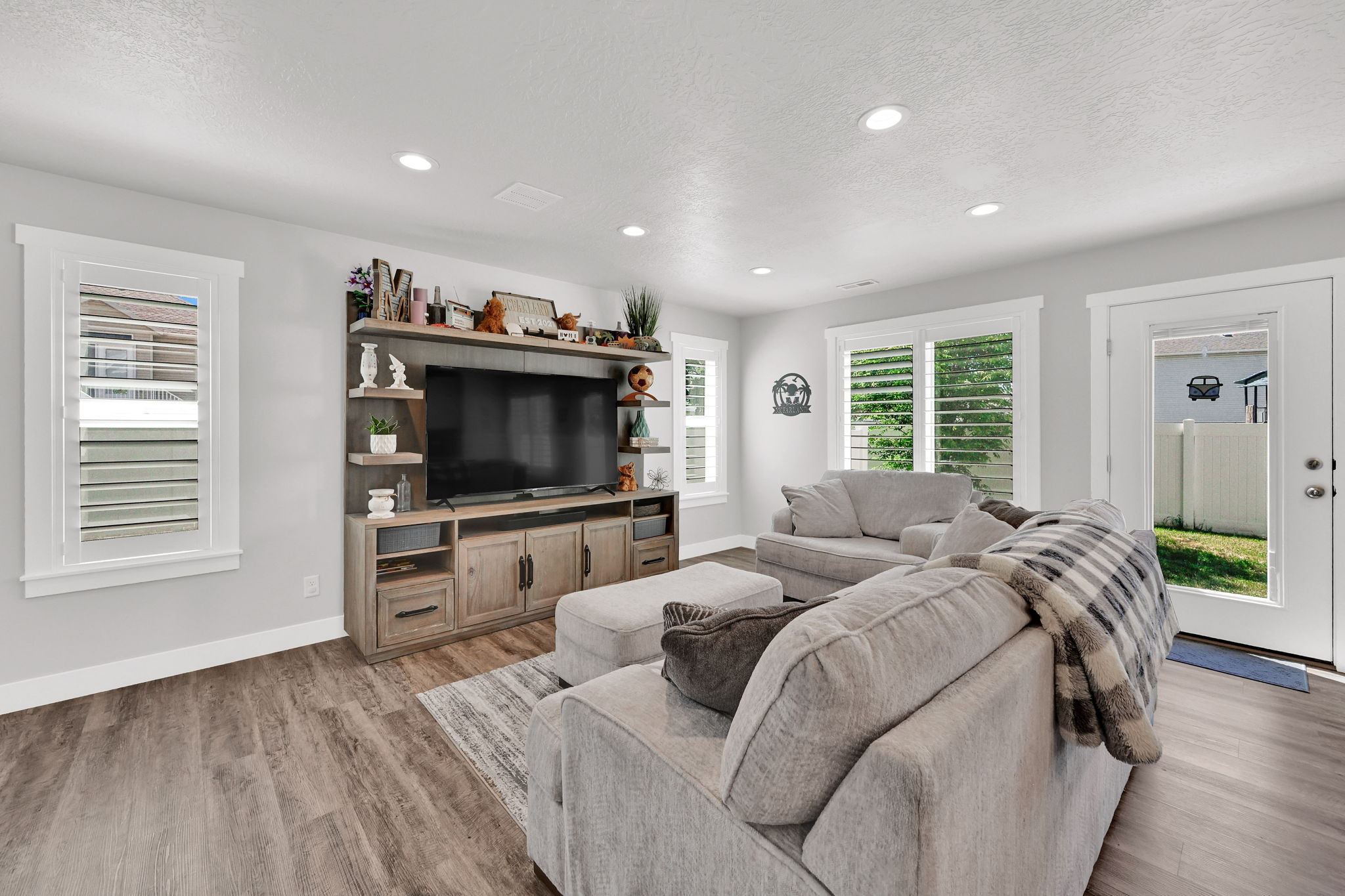 Open-concept living space/kitchen  featuring LVP flooring, recessed lighting, and white plantation shutters