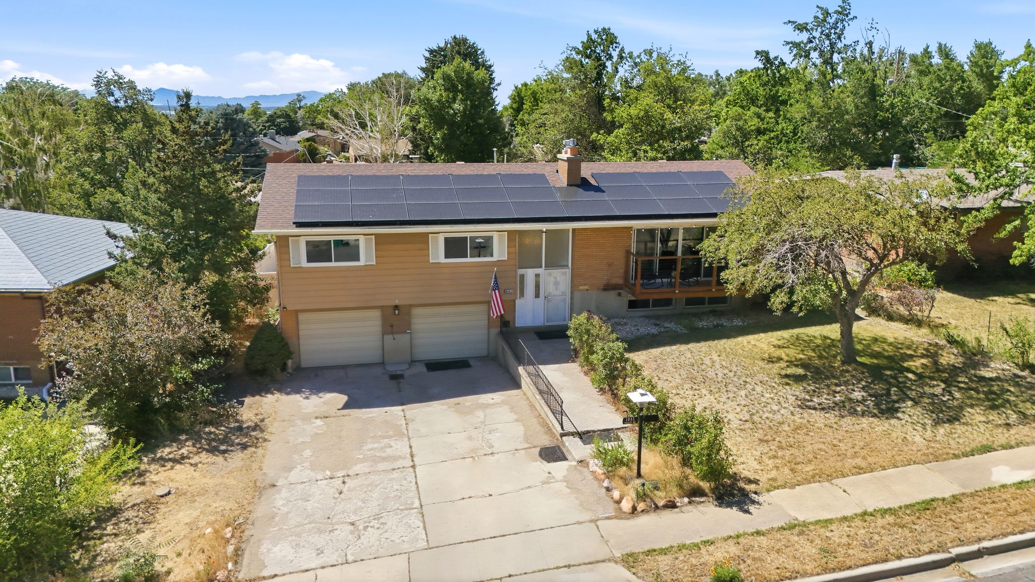 Split-level residence featuring a prominent solar panel array, a two-car garage, and a concrete driveway