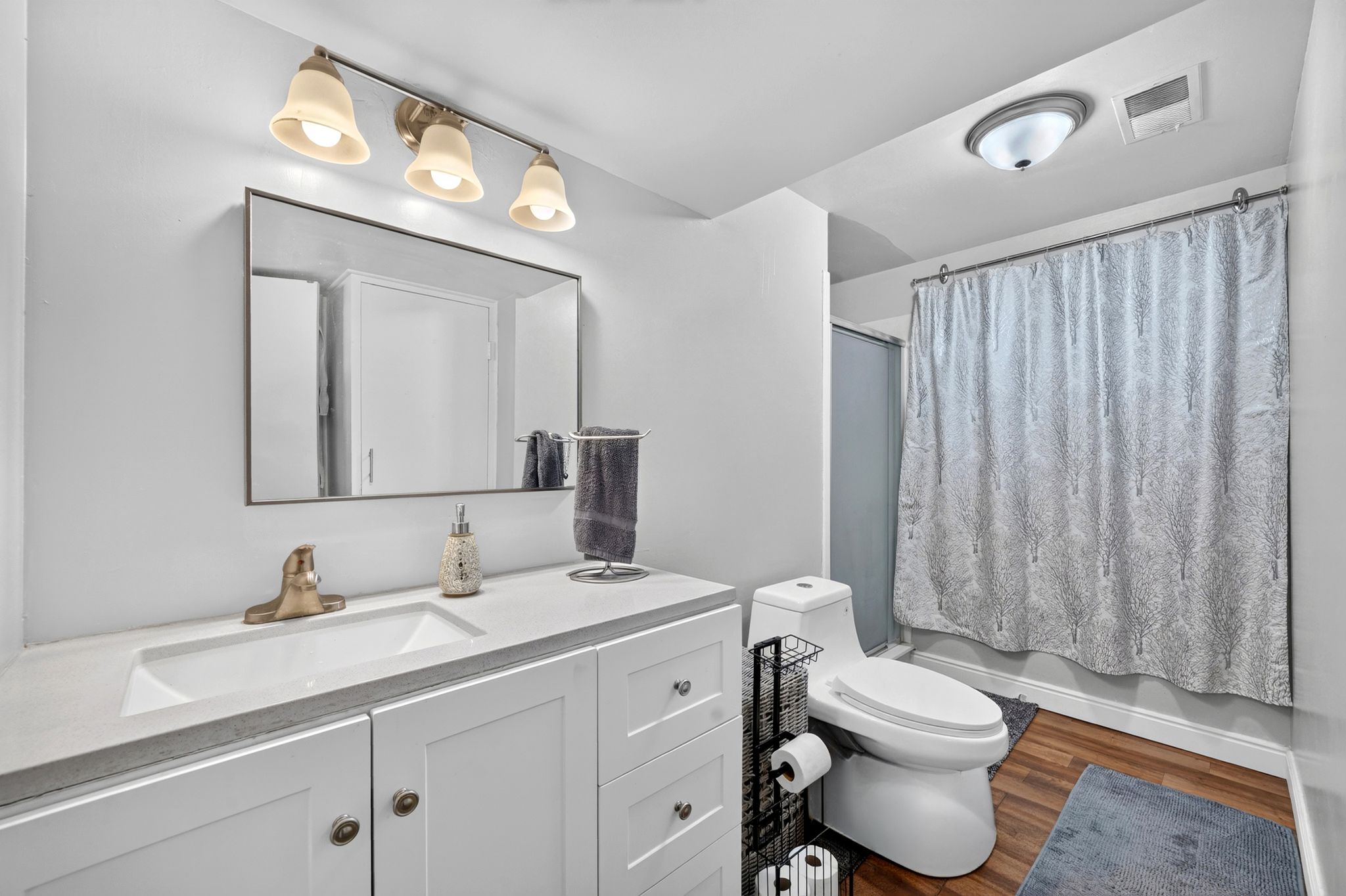 Bathroom featuring a white vanity with integrated sink, rectangular mirror, and a three-light fixture