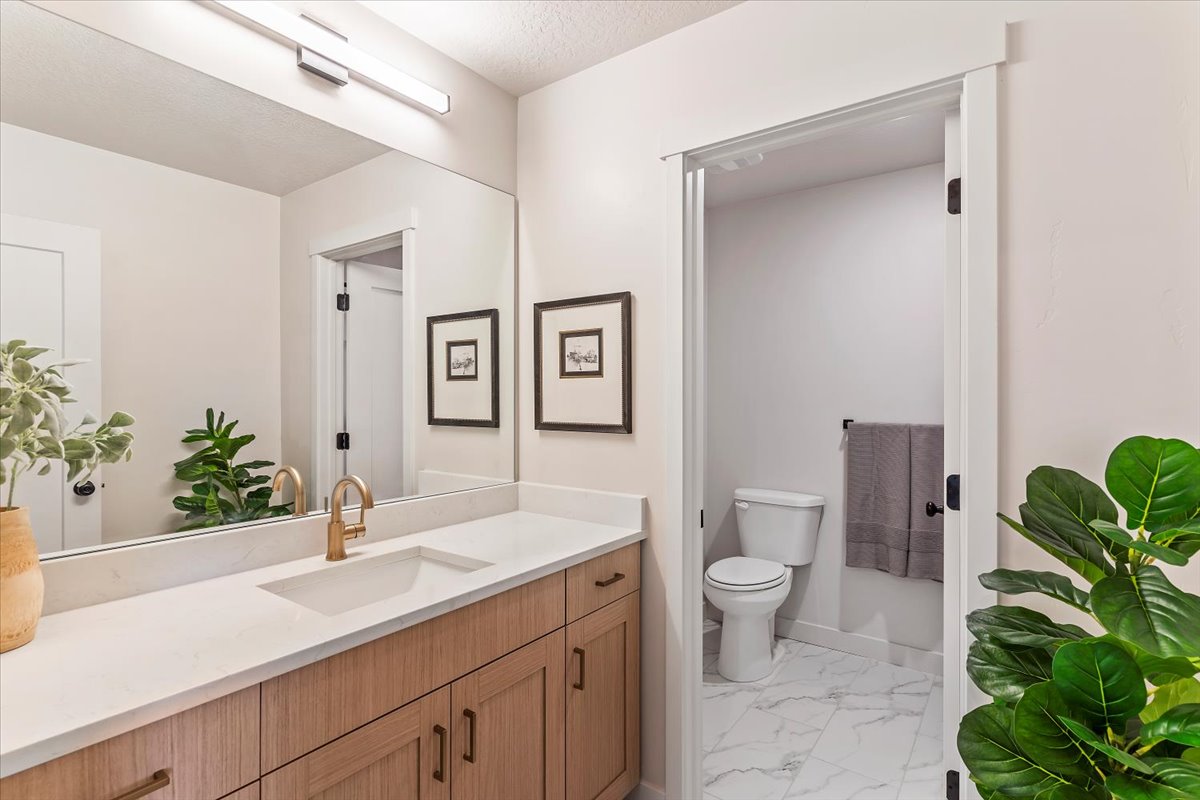 Bathroom vanity with a single integrated sink, brass-finish faucet, and light wood-finish cabinetry