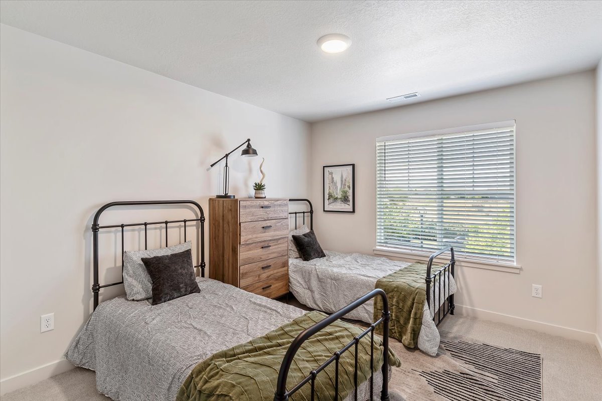 Light-filled room featuring wall-to-wall carpeting, neutral wall tones, a large window with blinds, and a flush-mount ceiling light