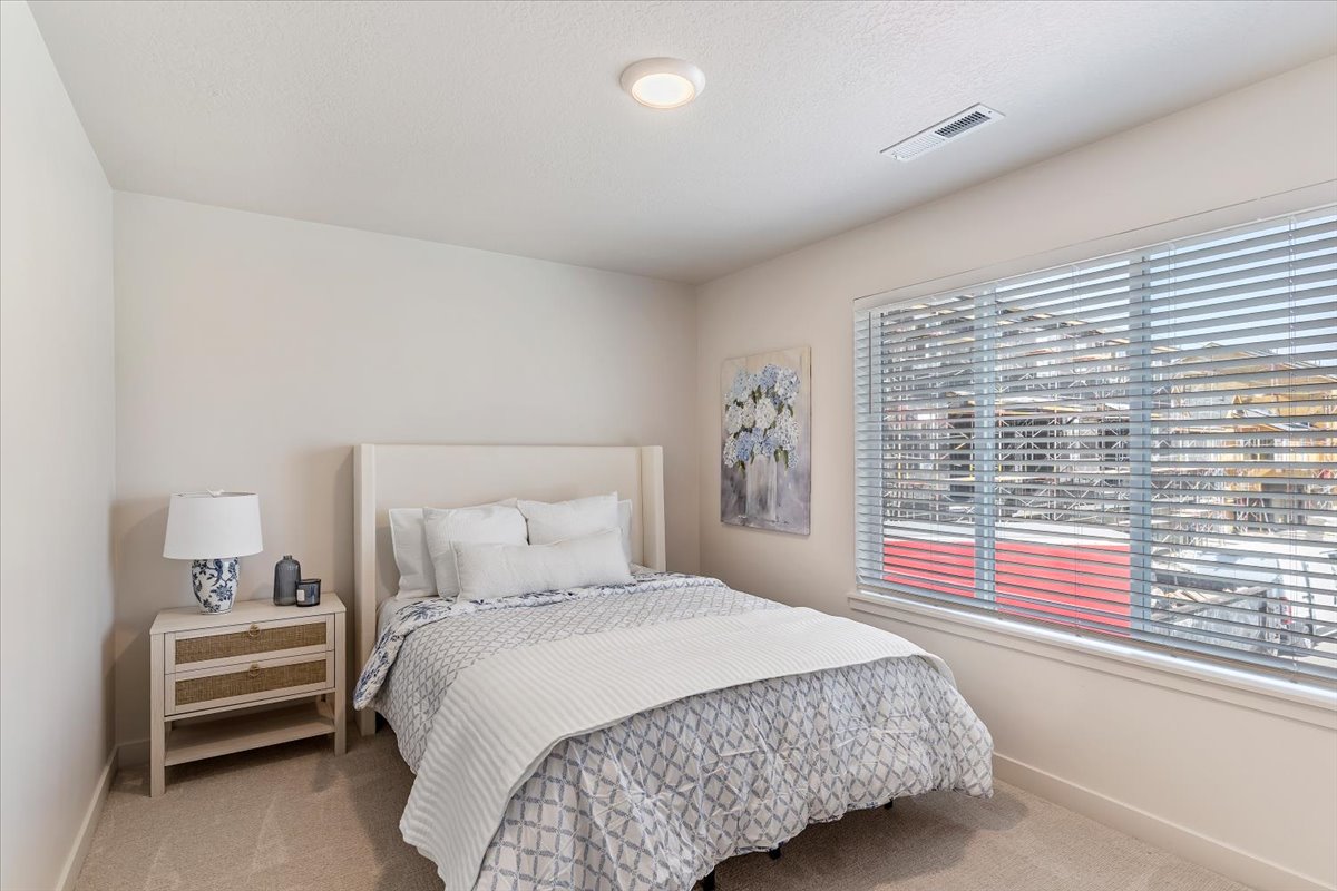 Bright room featuring a large window with blinds, neutral wall paint, and plush carpet flooring