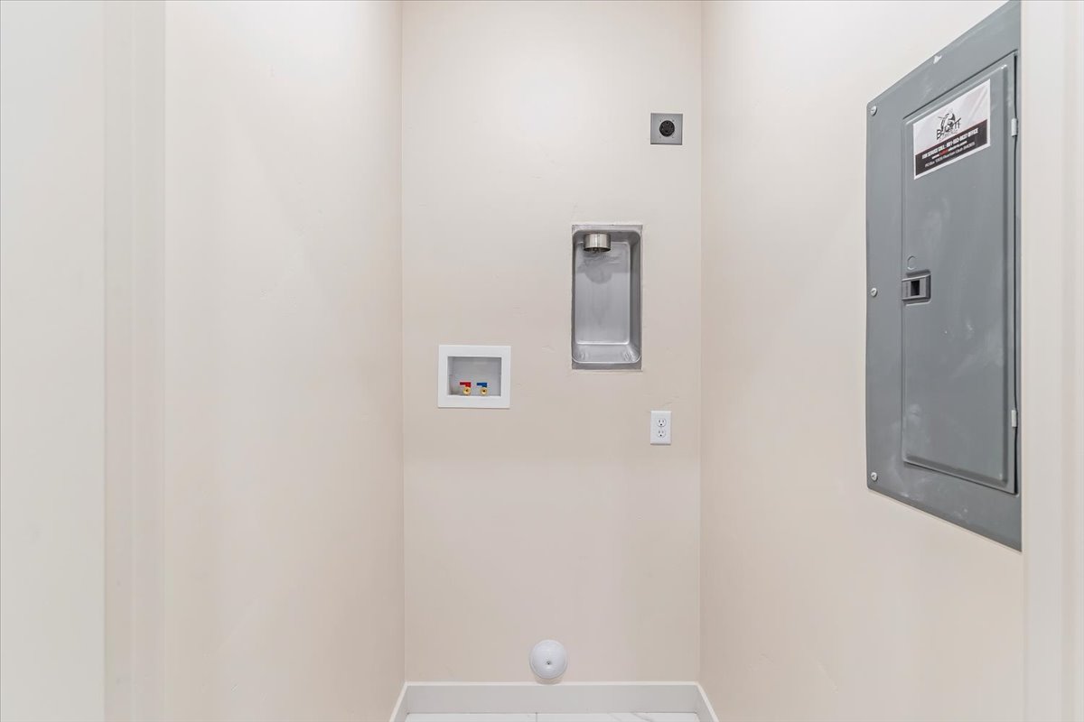 Dedicated laundry area featuring a wall-mounted electrical panel, washer hookups, and a floor drain