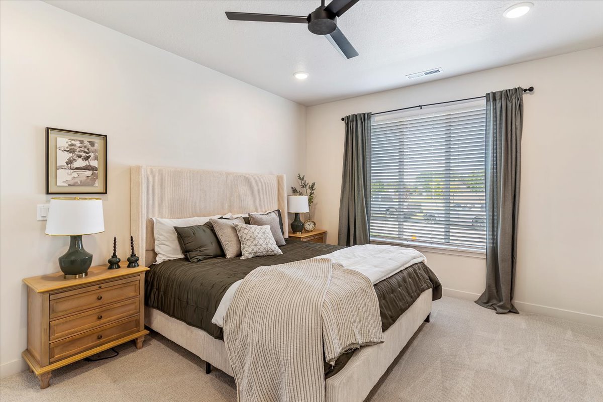 Carpeted bedroom featuring a large window with blinds and drapes, a ceiling fan, and recessed lighting