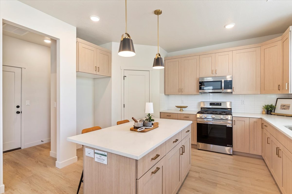 Modern kitchen featuring light wood-finish cabinetry, stainless steel appliances, a center island with a white countertop, and recessed lighting