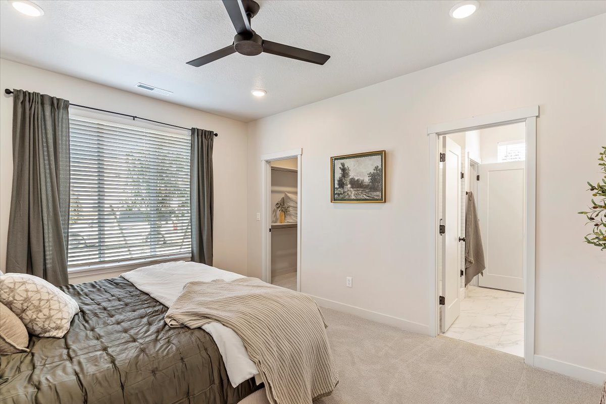 Carpeted bedroom featuring a large window with blinds, recessed lighting, and a ceiling fan